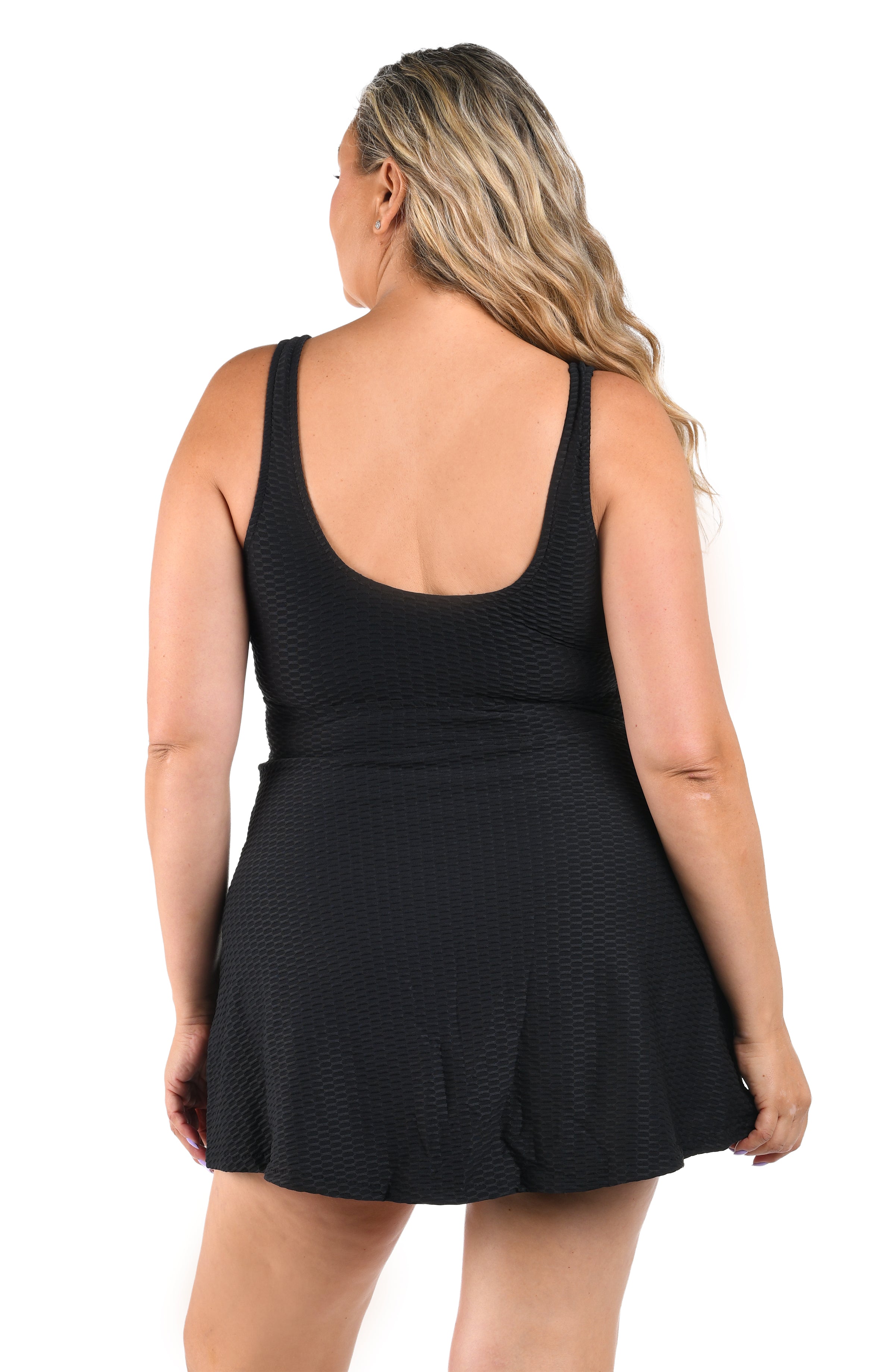 Woman wearing a black one piece swim dress with a textured pattern on a white background