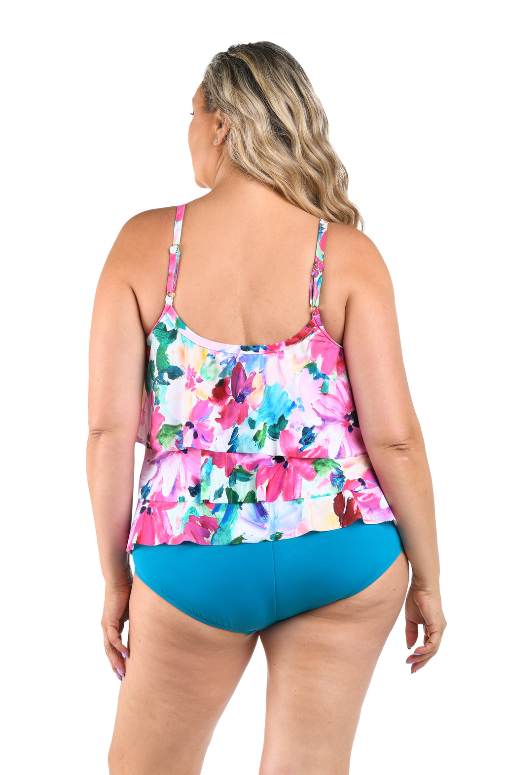 Woman wearing a colorful floral tankini top and emerald colored bottoms on a white background