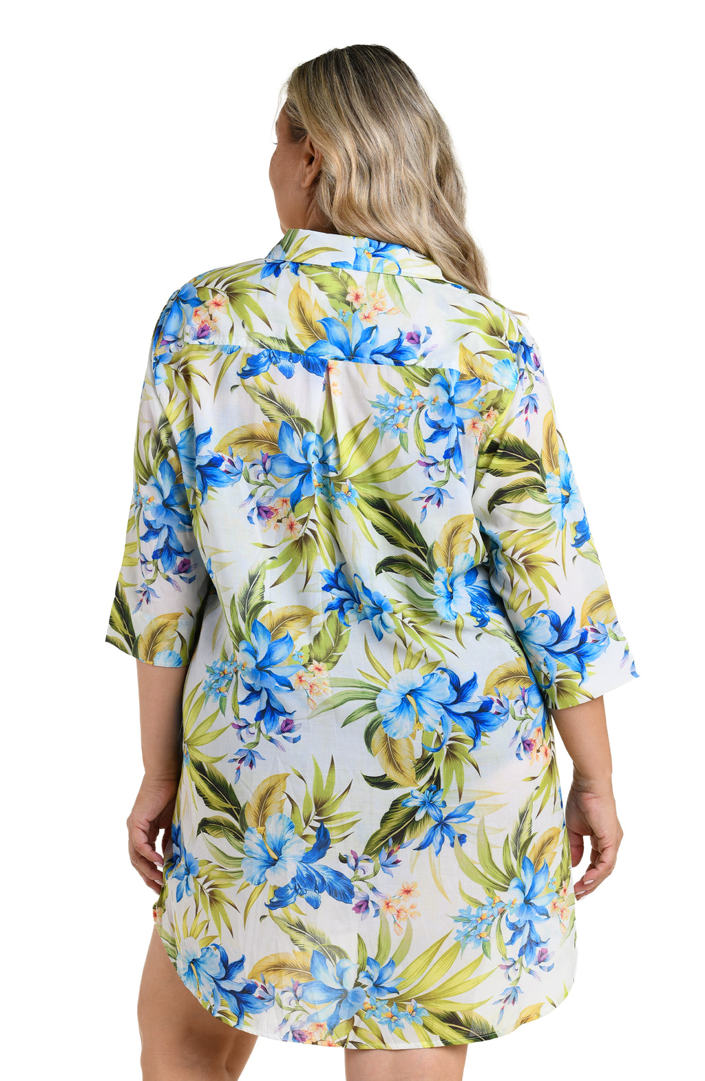 Woman wearing a floral cover up shirt with blue and green flowers on a white background