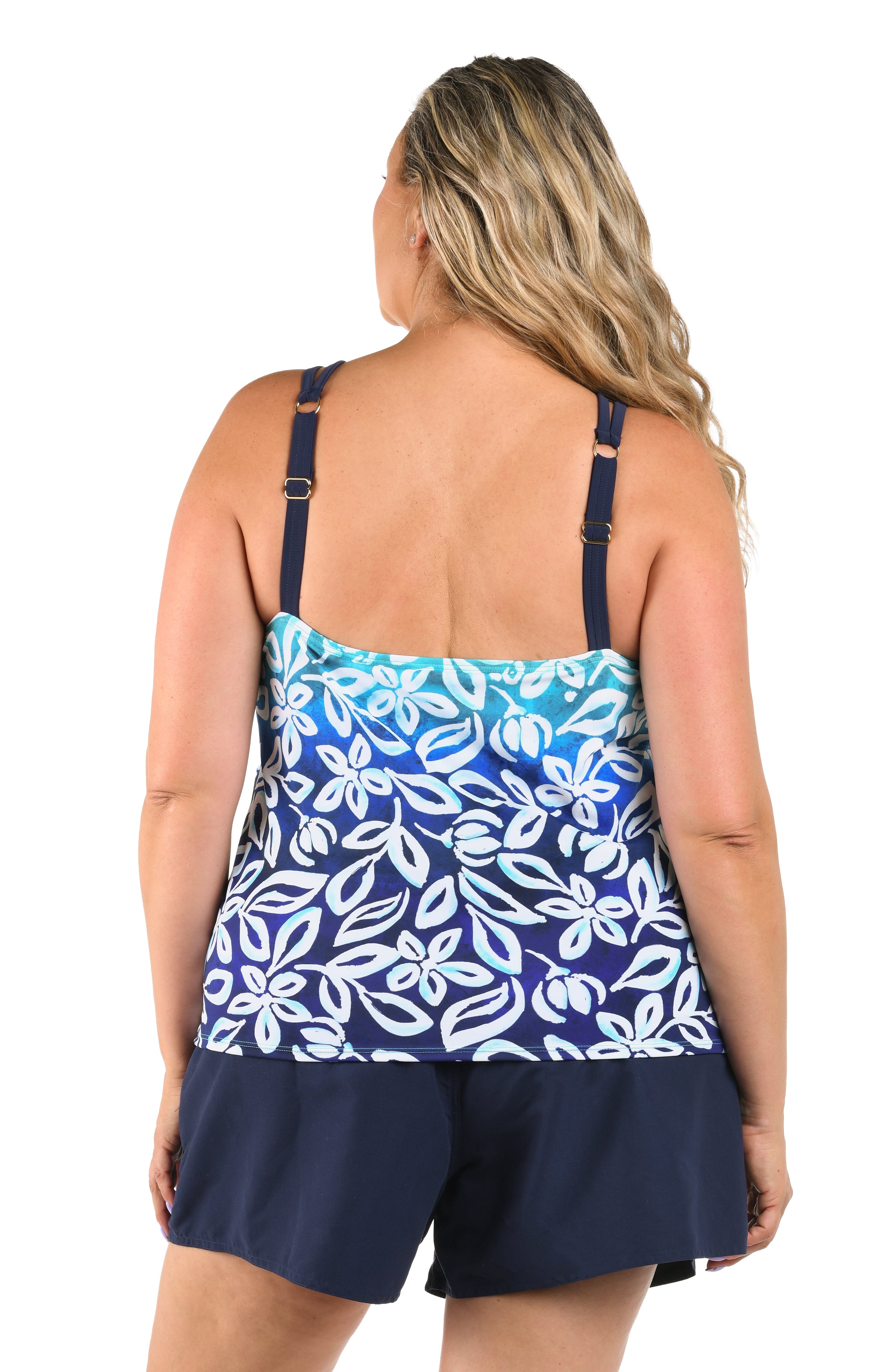 Woman wearing a blue floral tank top and navy shorts on a white background