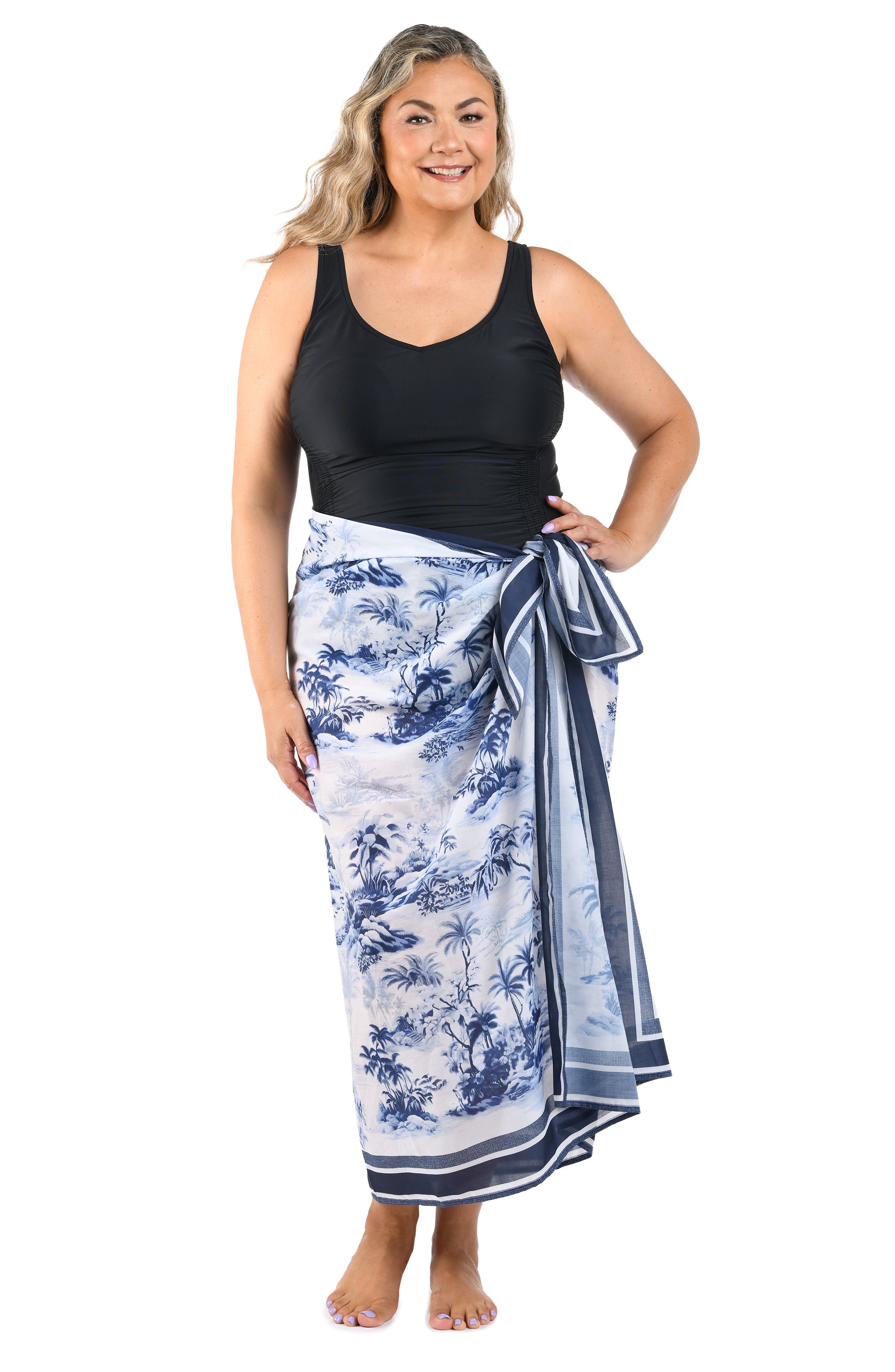 Full body front image of model wearing a multicolored white and blue tropical pareo which is tied to the side. 