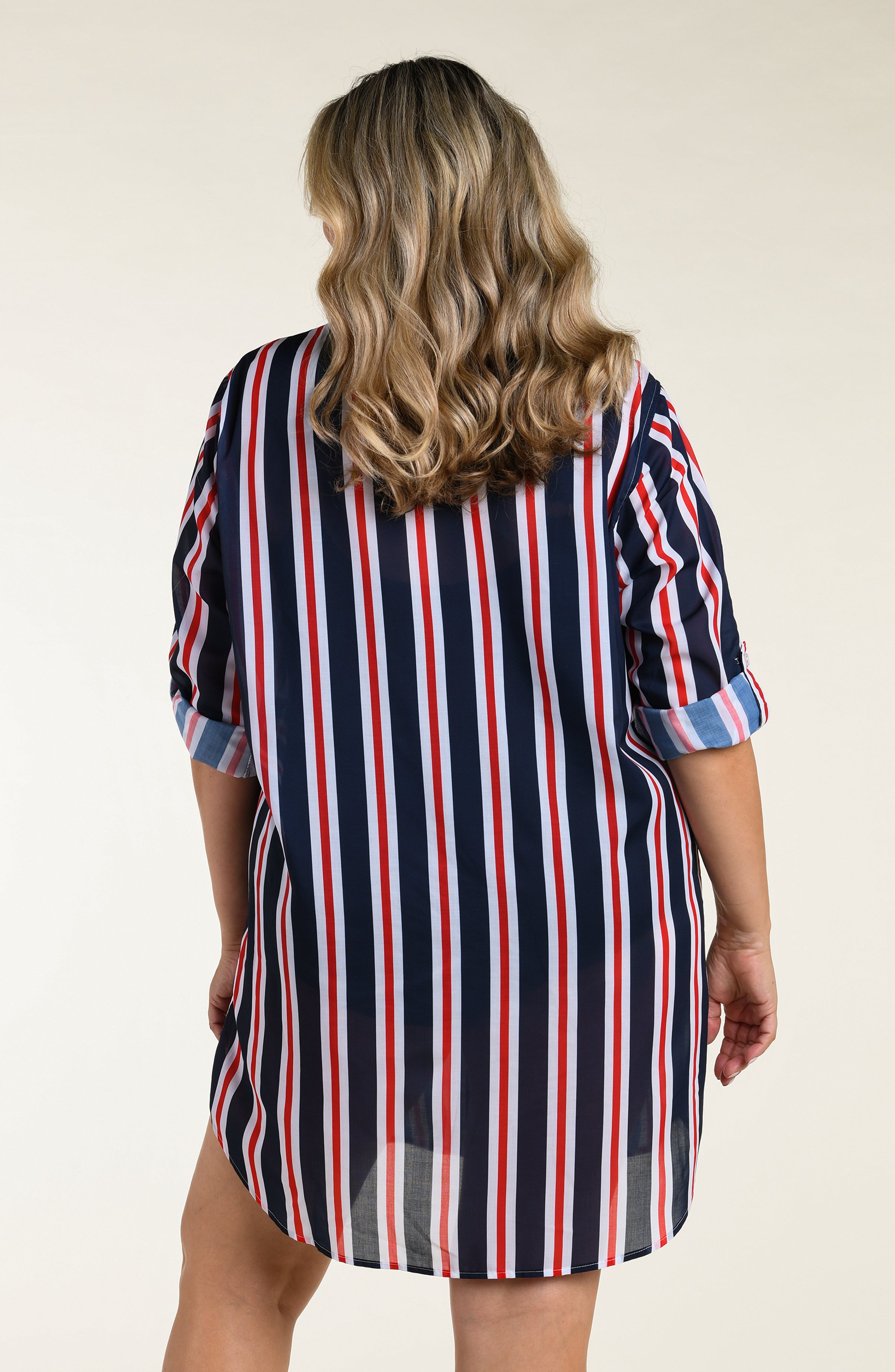 Woman wearing a navy, red, and white striped button down tunic against a plain background
