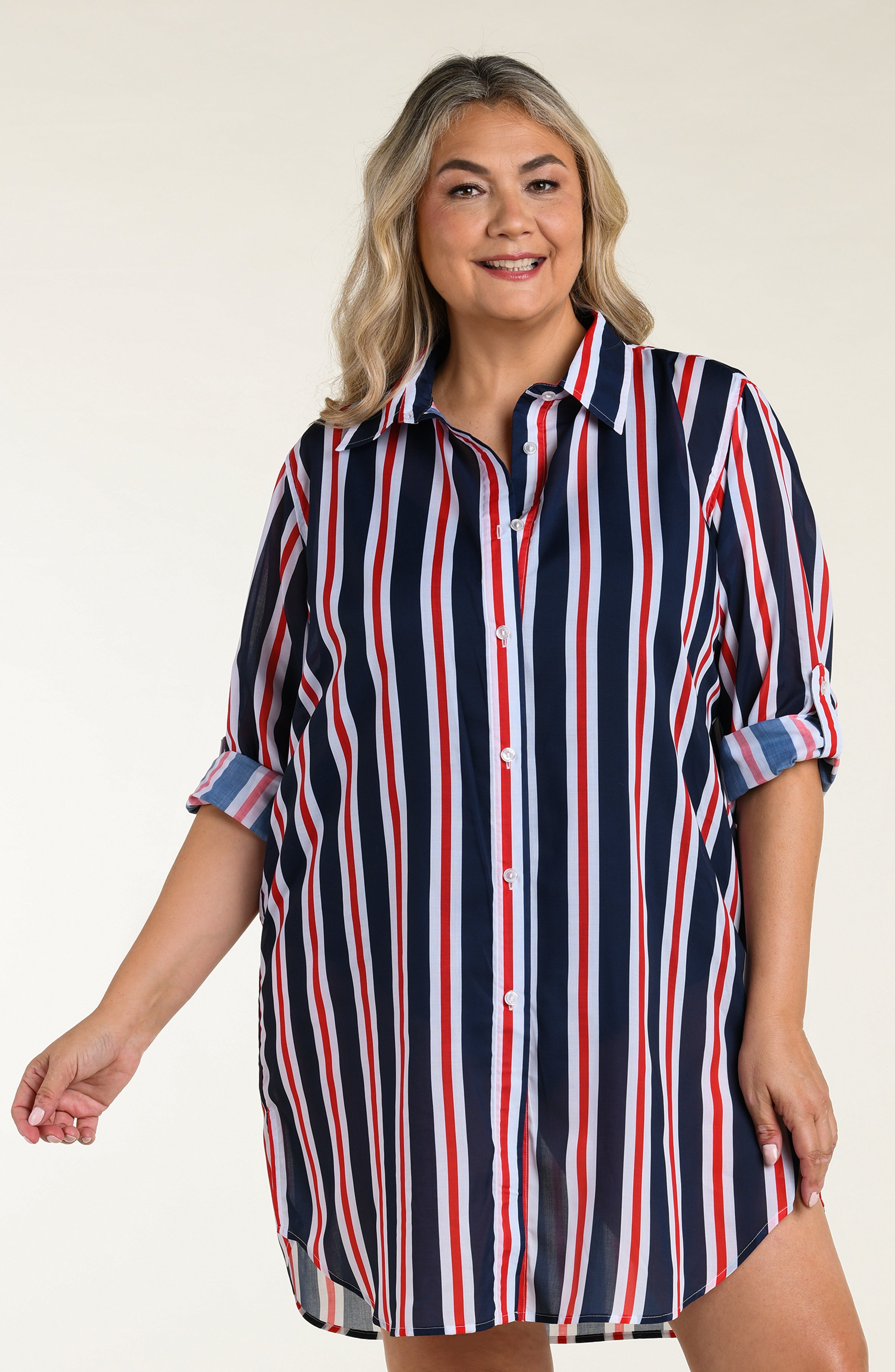 Woman wearing a navy, red, and white striped button down tunic against a plain background