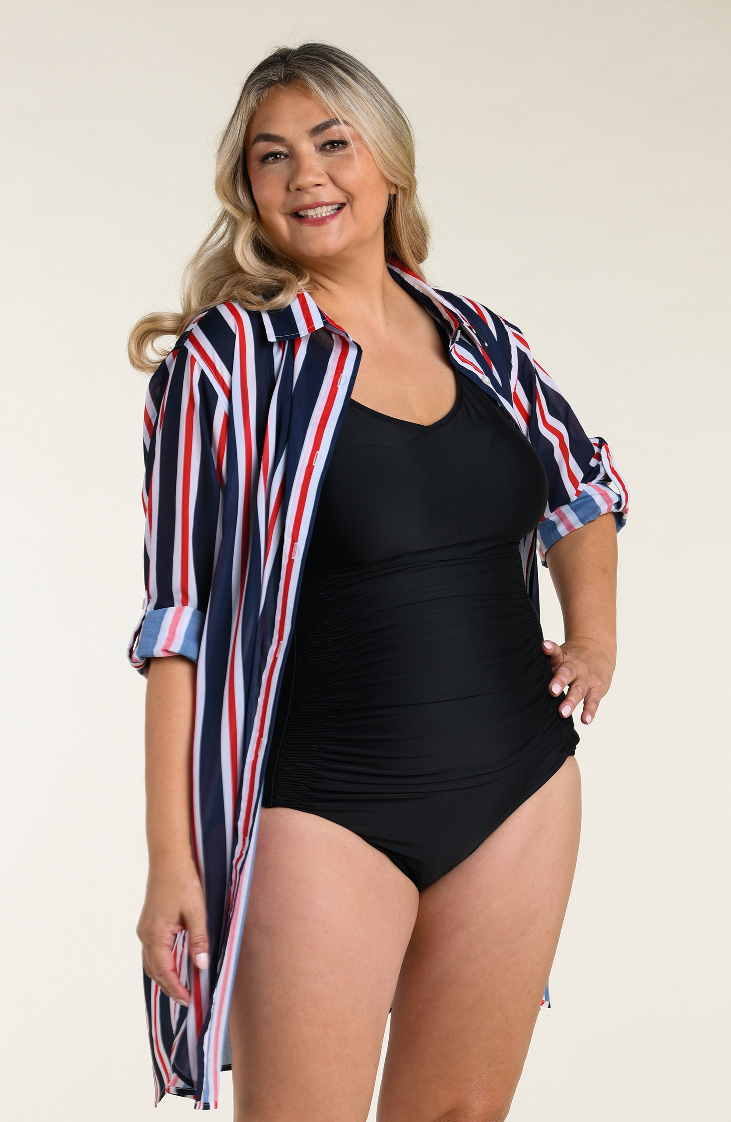 Woman wearing a navy, red, and white striped button down tunic against a plain background