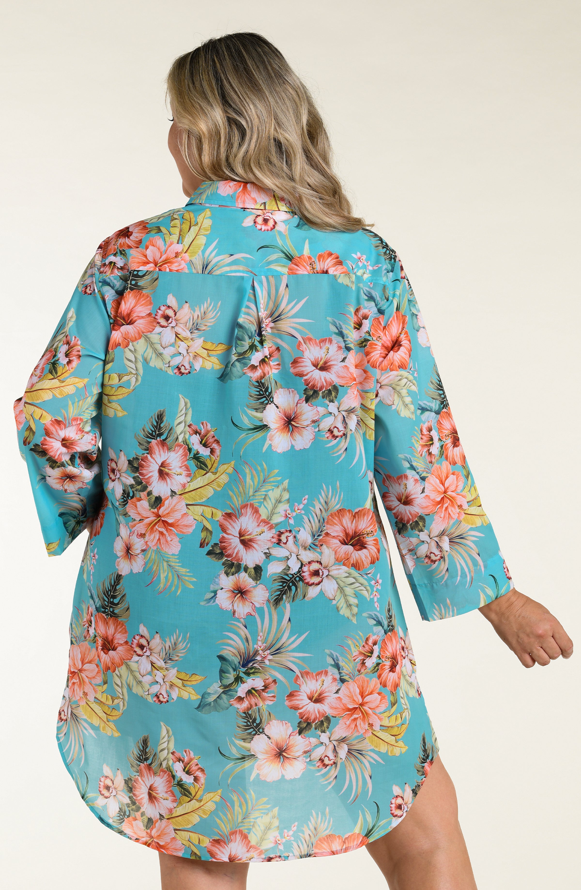 Woman wearing a floral cover up tunic with a white background