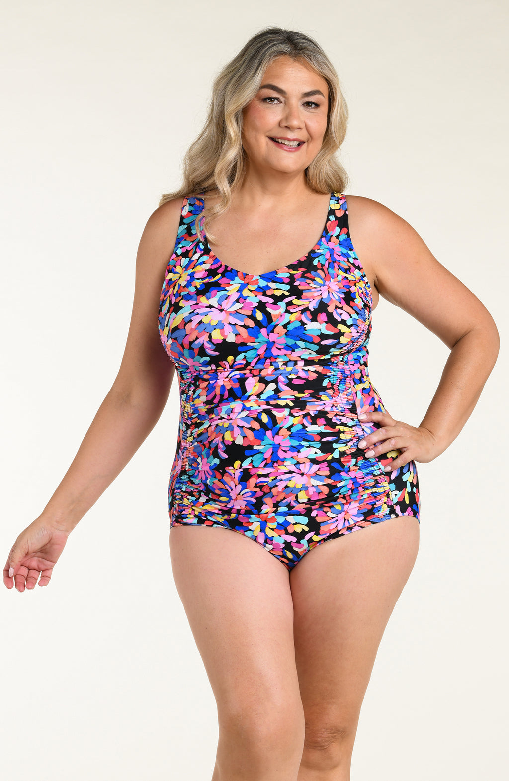 Woman wearing a colorful floral one-piece swimsuit on a beige background