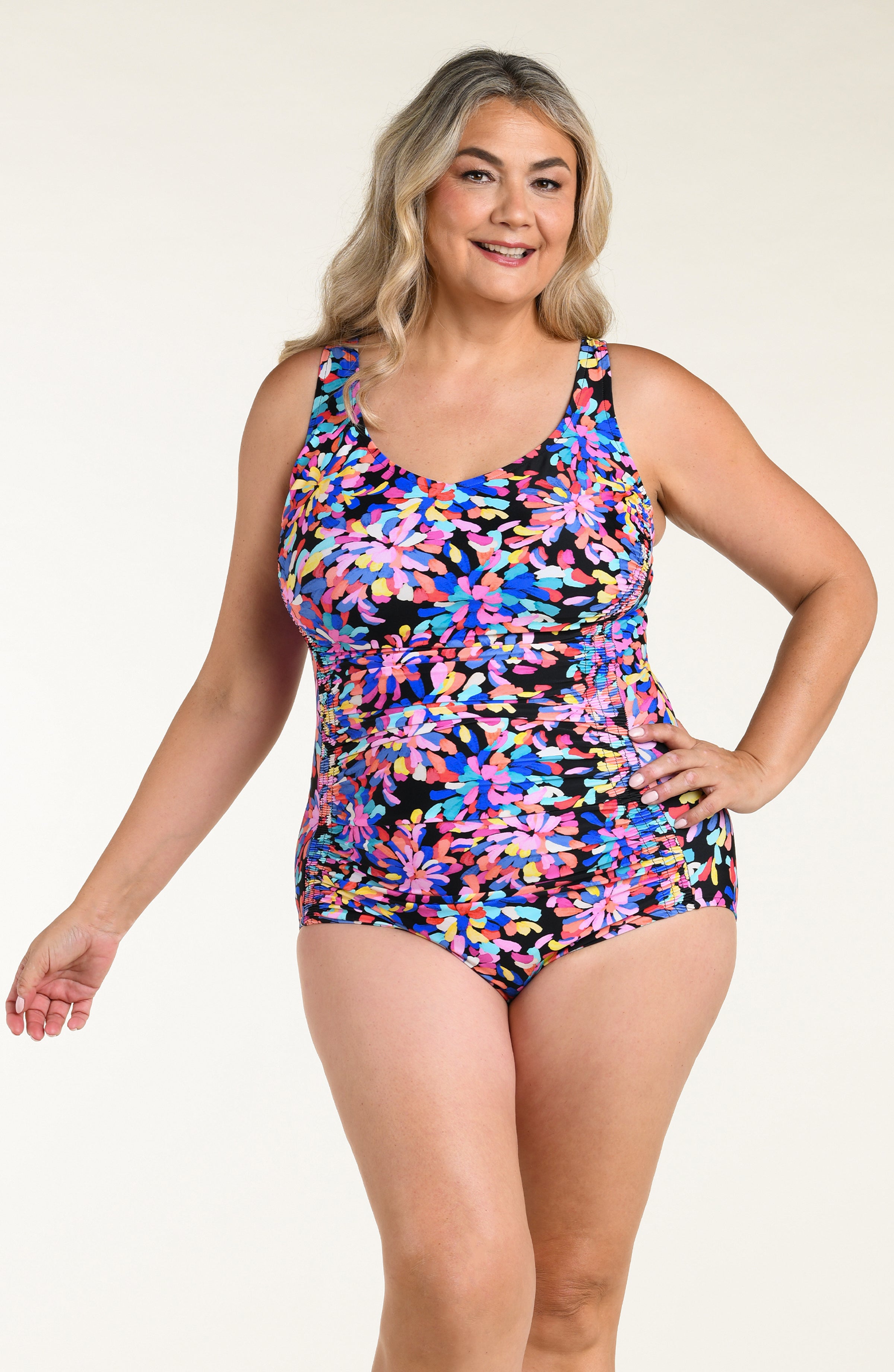 Woman wearing a colorful floral one-piece swimsuit on a beige background