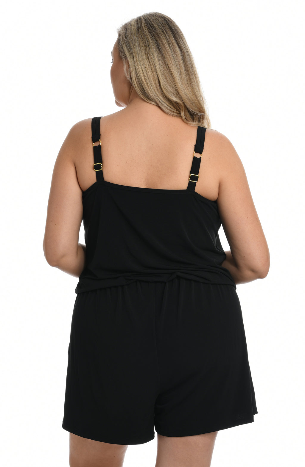 Woman wearing a black swim romper one piece against a white background