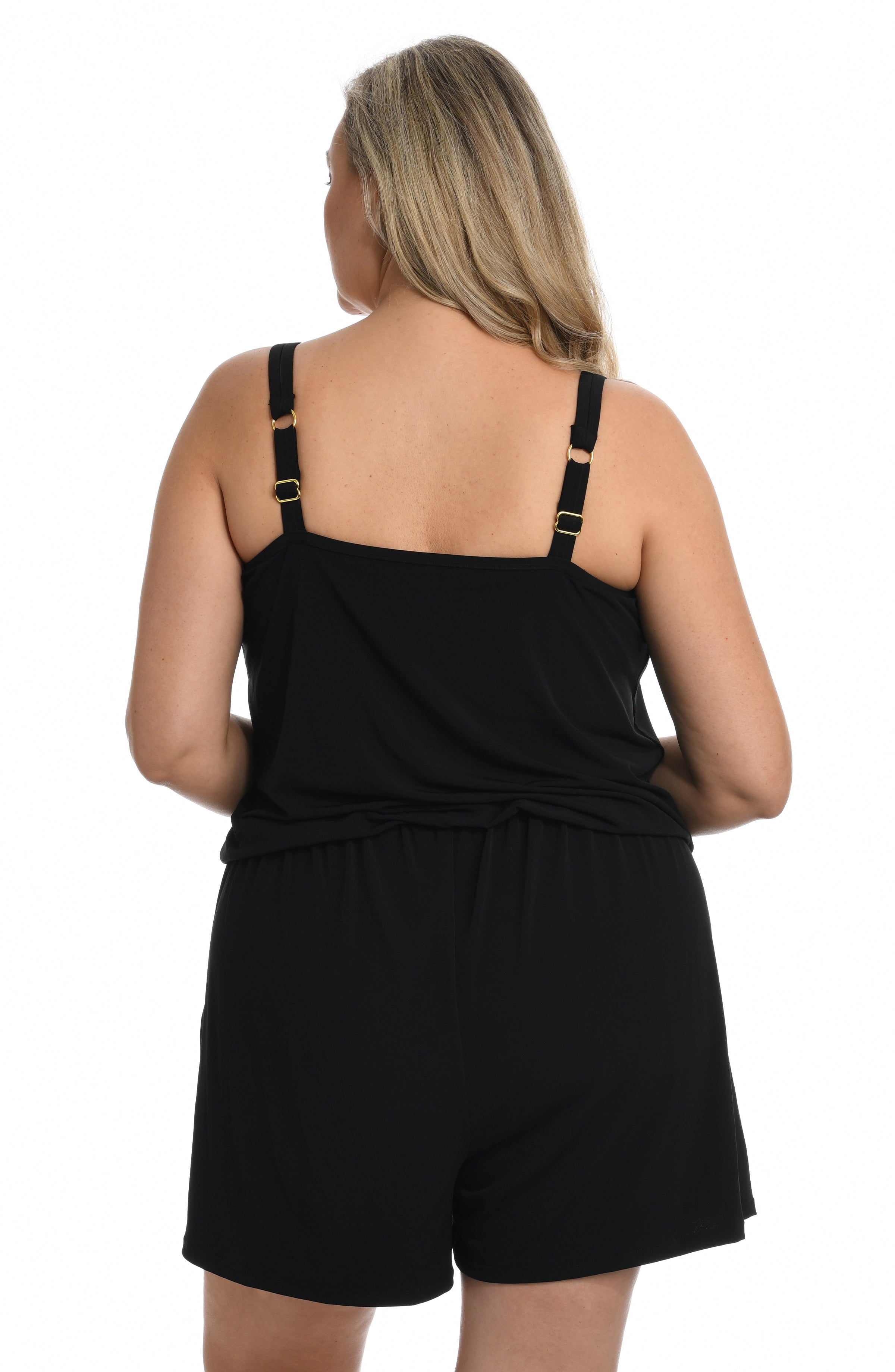 Woman wearing a black swim romper one piece against a white background