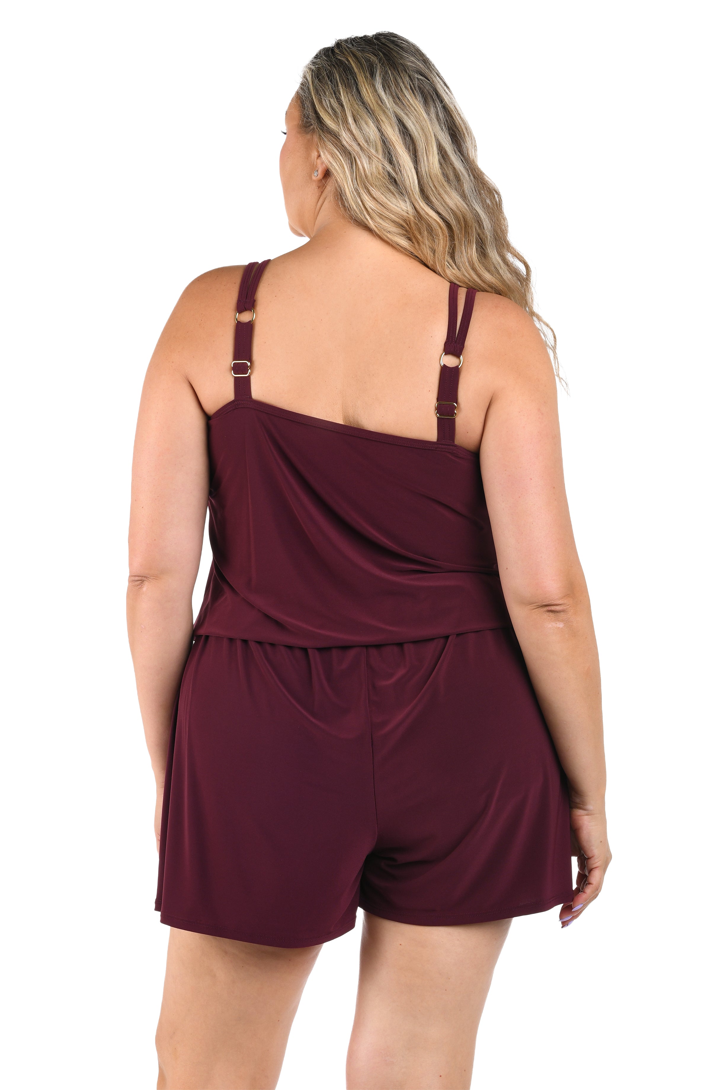 Woman wearing a burgundy romper one piece on a white background.