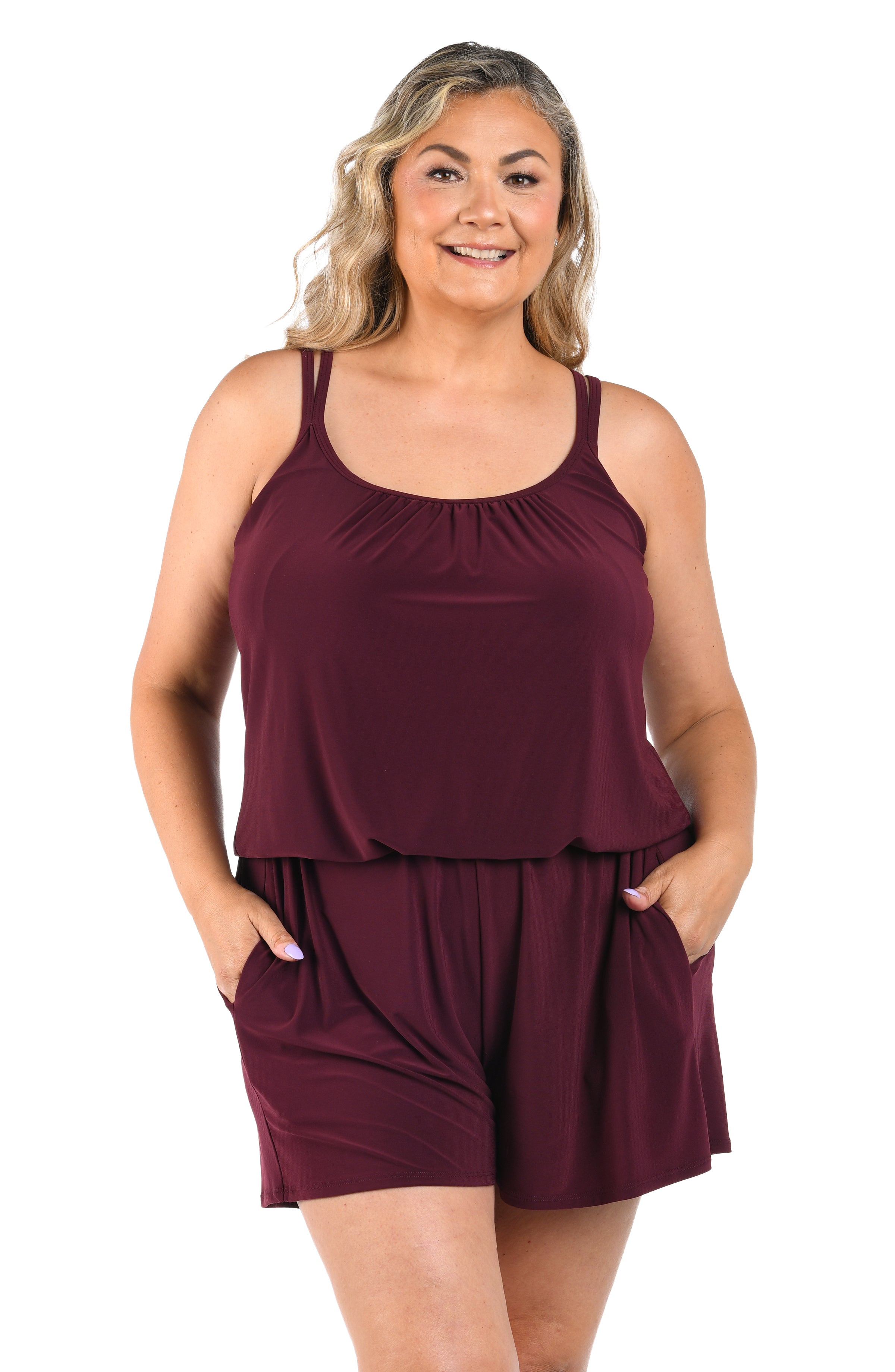 Woman wearing a burgundy romper one piece on a white background.