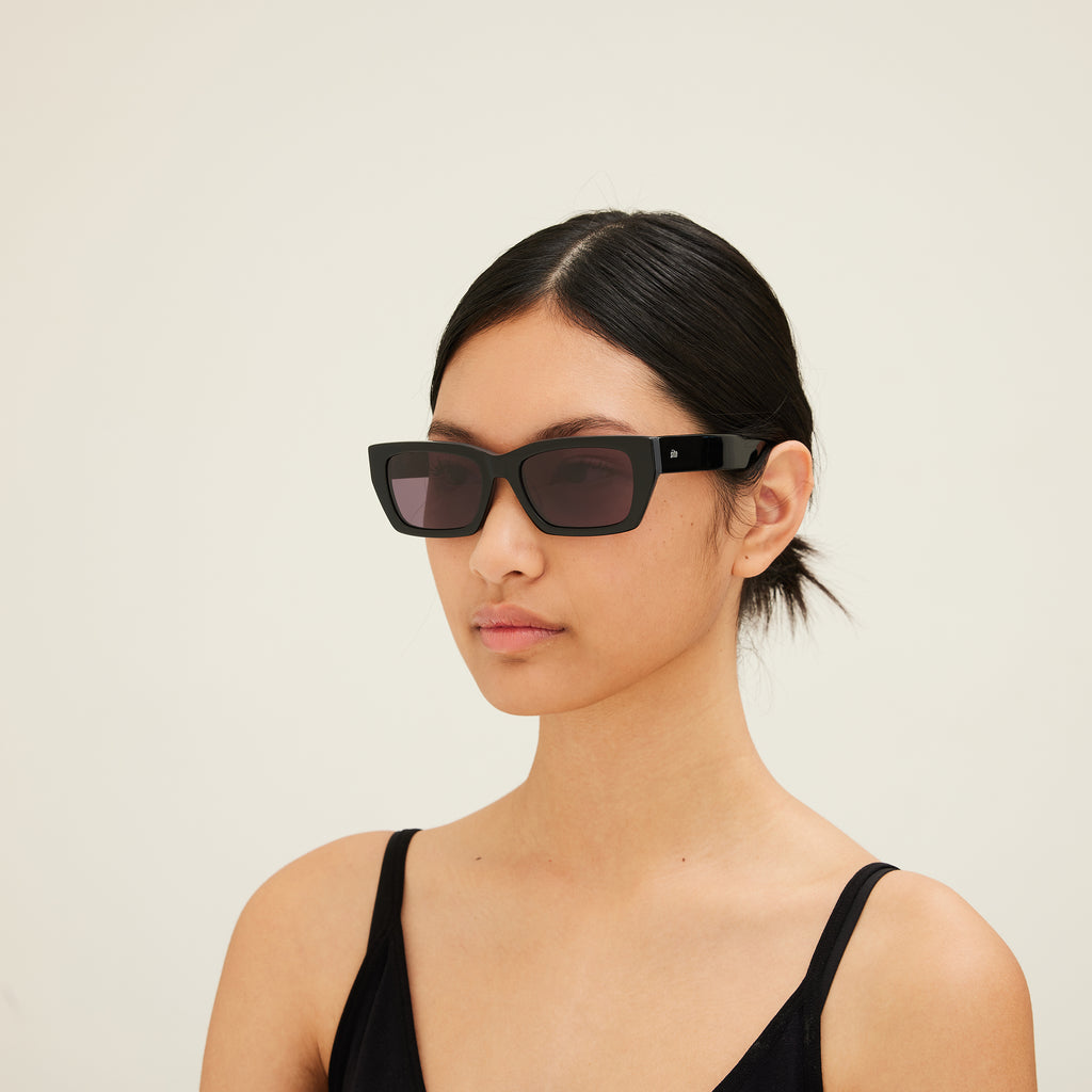 Woman wearing black sunglasses against a plain background