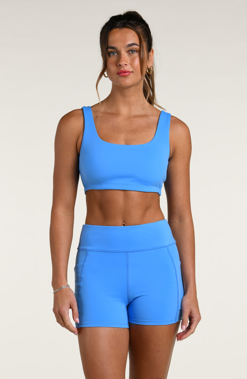 Woman wearing a blue sports bra and matching bike short against a white background