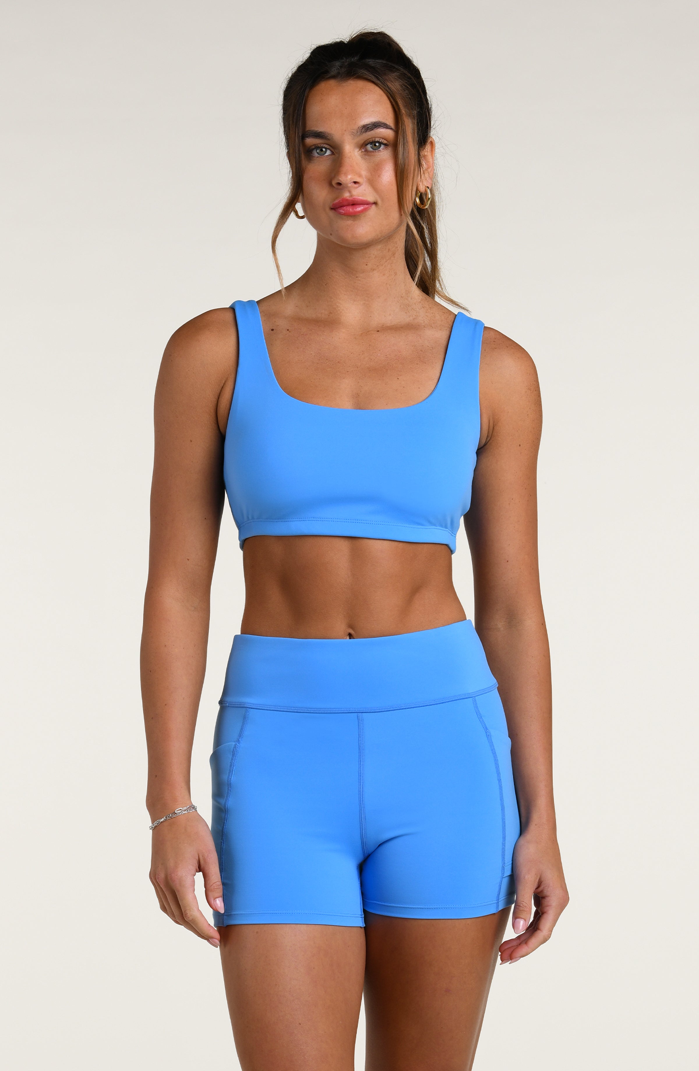 Woman wearing a blue sports bra and matching bike short against a white background
