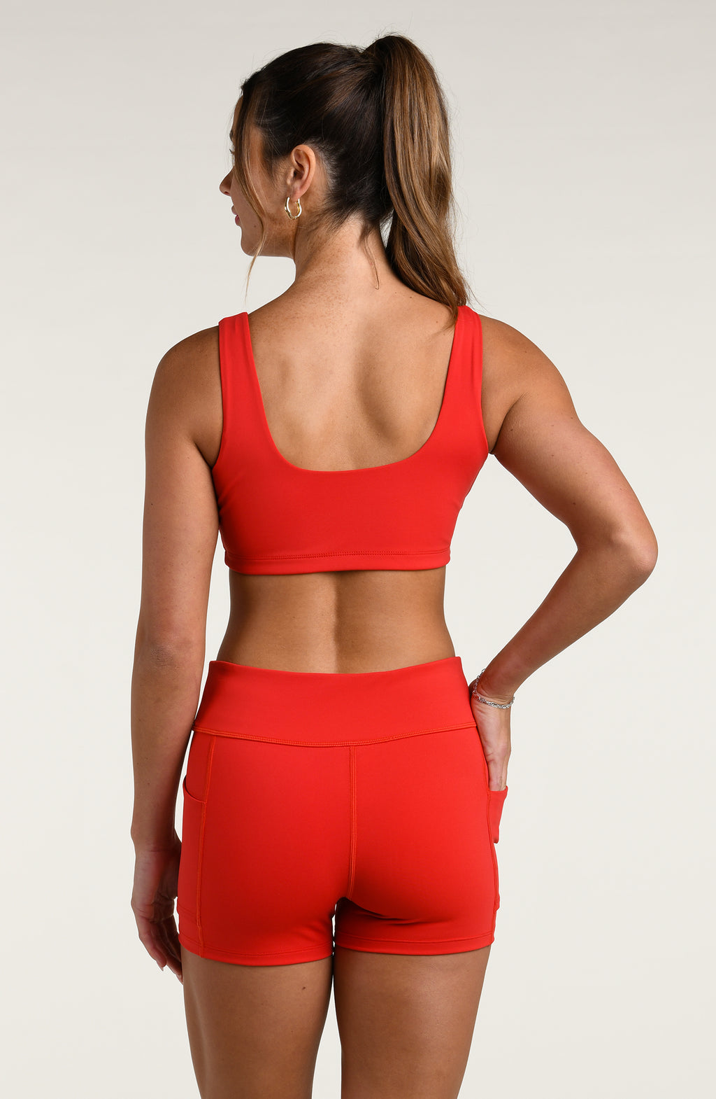 Woman wearing a red sports bra and matching bike short against a white background