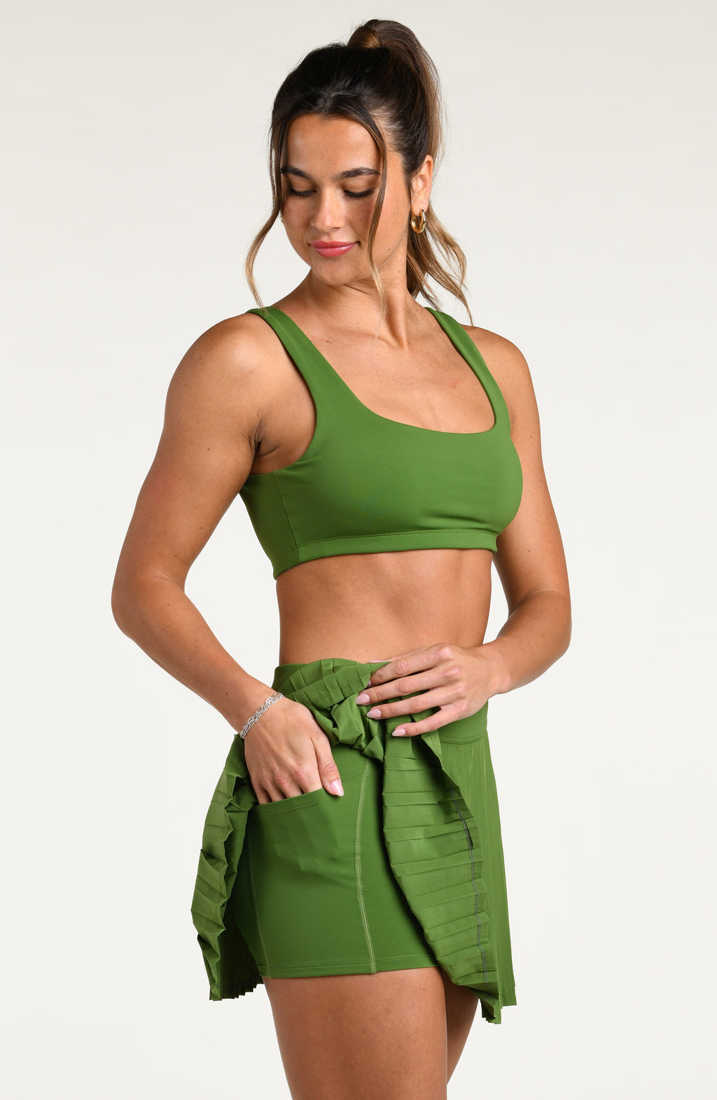 Woman wearing a green sports bra and matching swim short against a white background