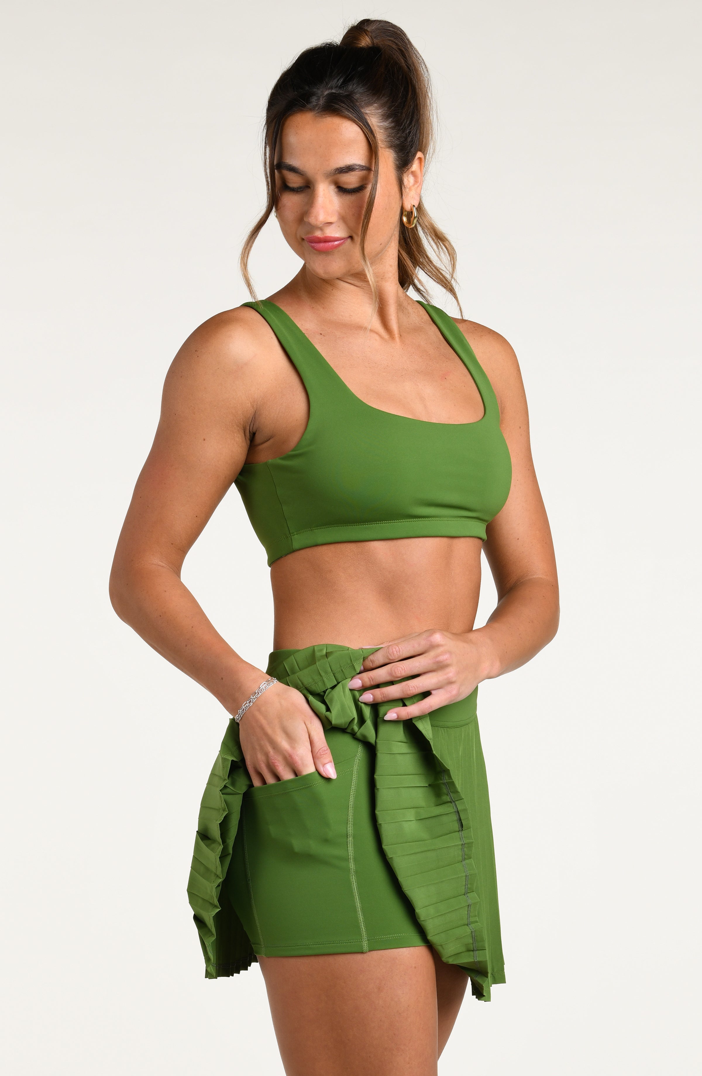 Woman wearing a green sports bra and matching swim short against a white background