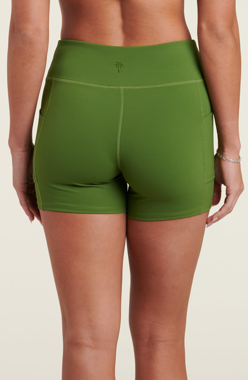 Woman wearing green biker shorts against a white background.