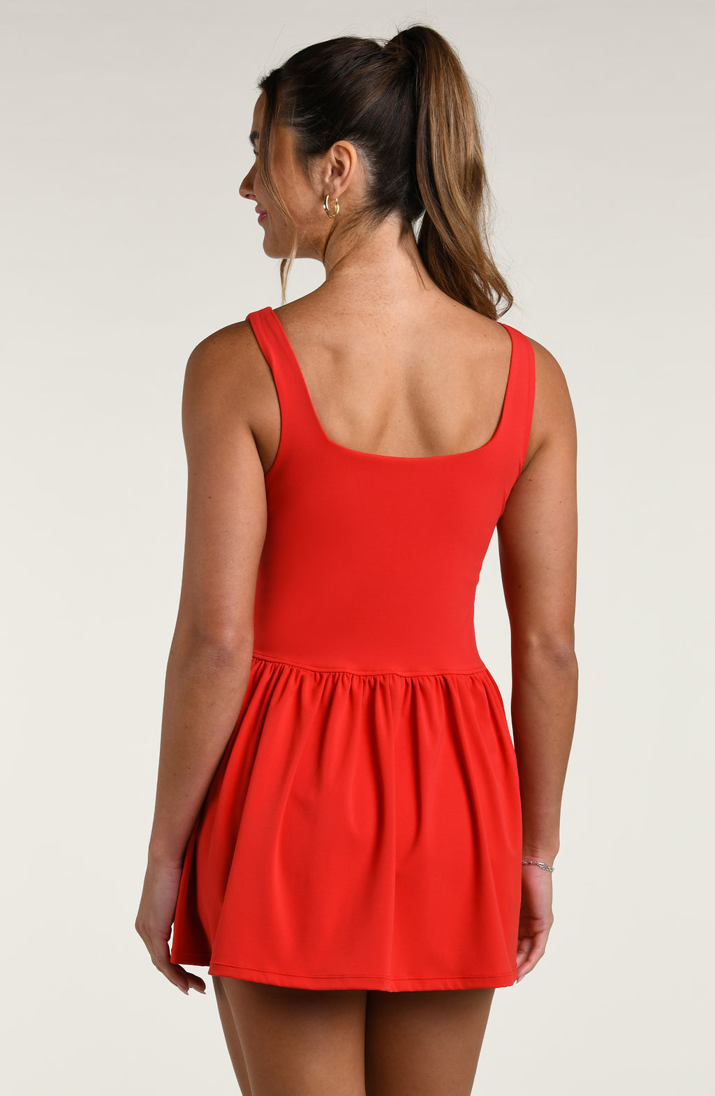 Woman wearing a red tennis dress against a white background.