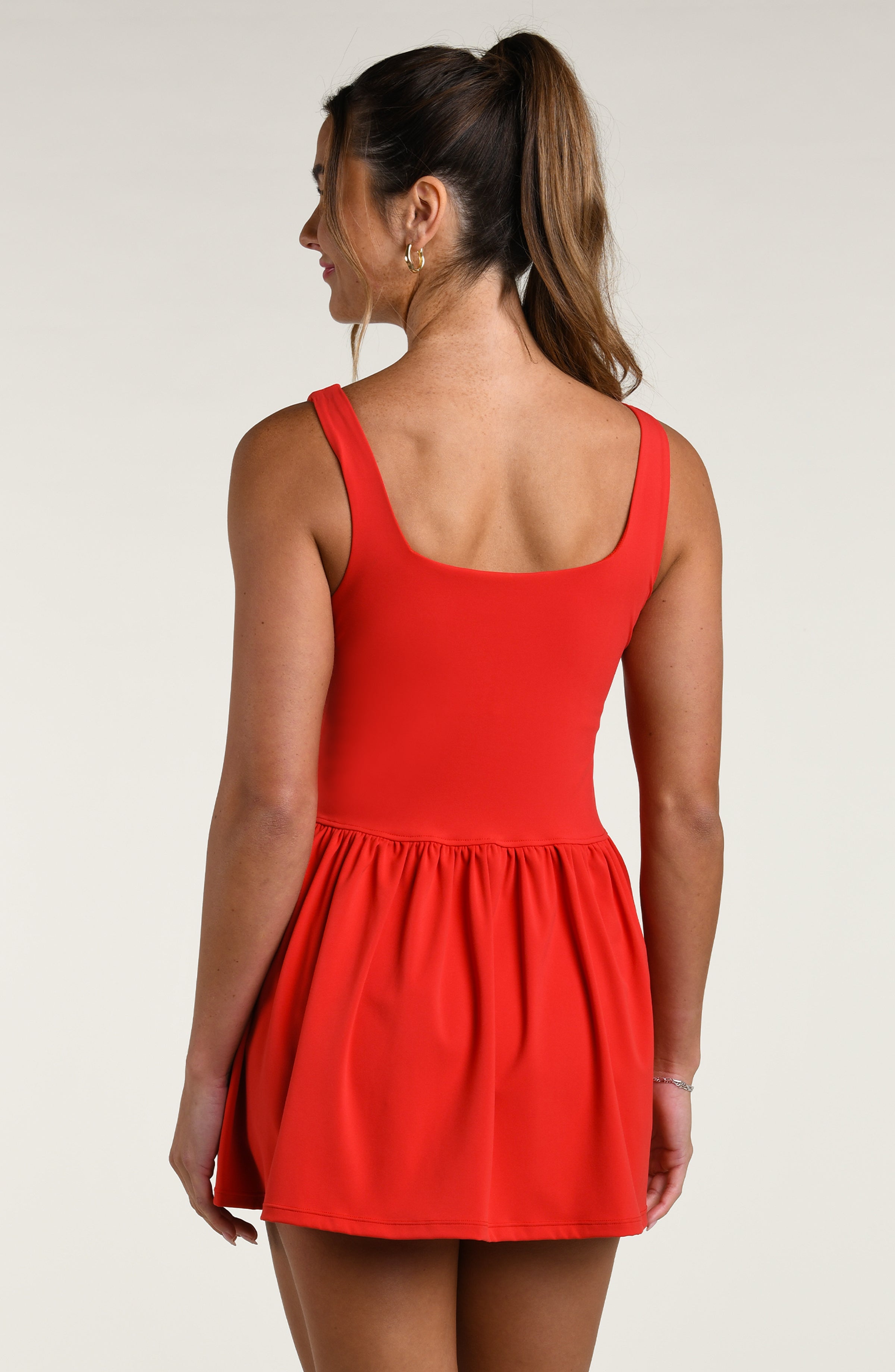 Woman wearing a red tennis dress against a white background.