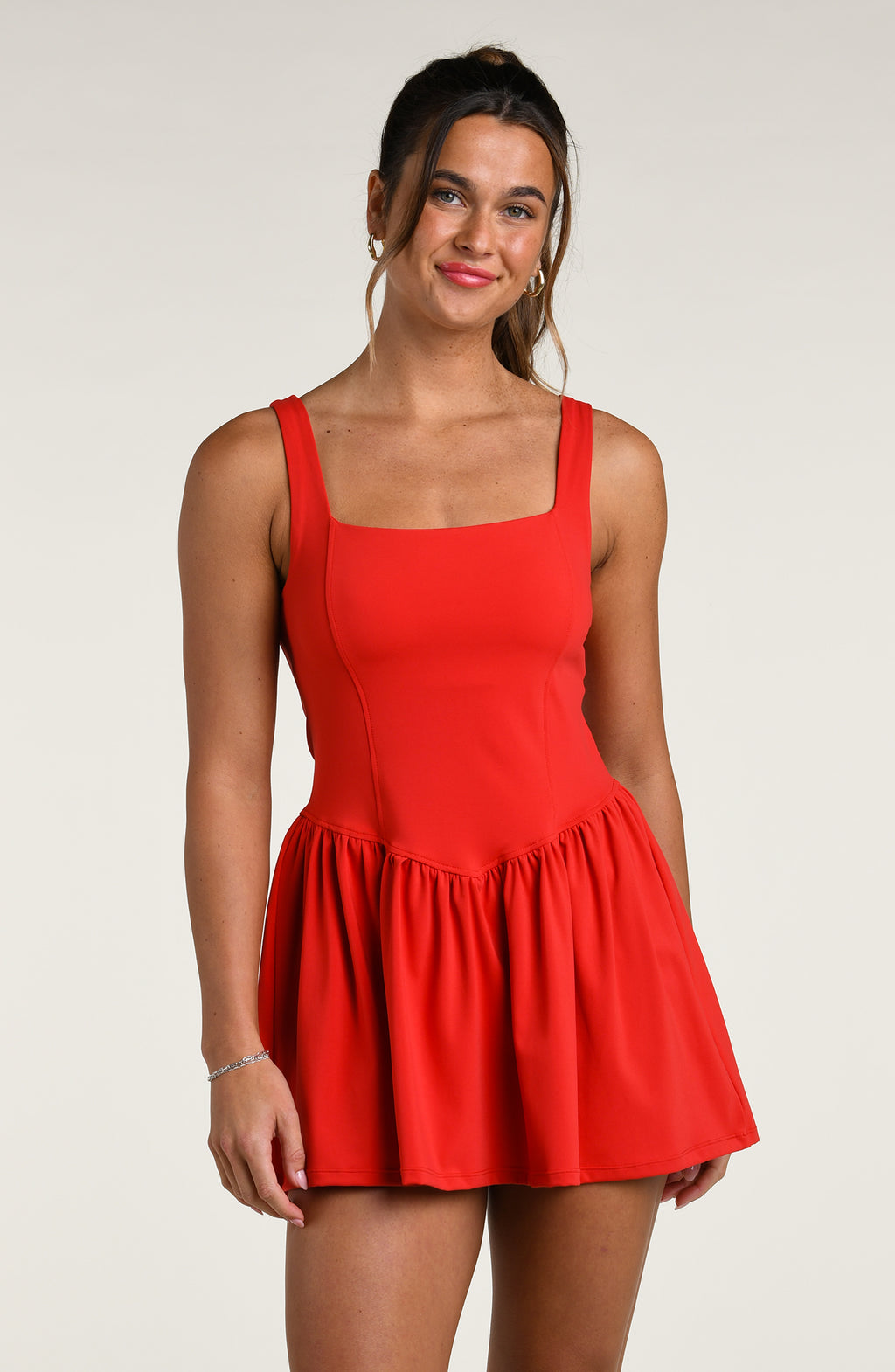 Woman wearing a red tennis dress against a white background.