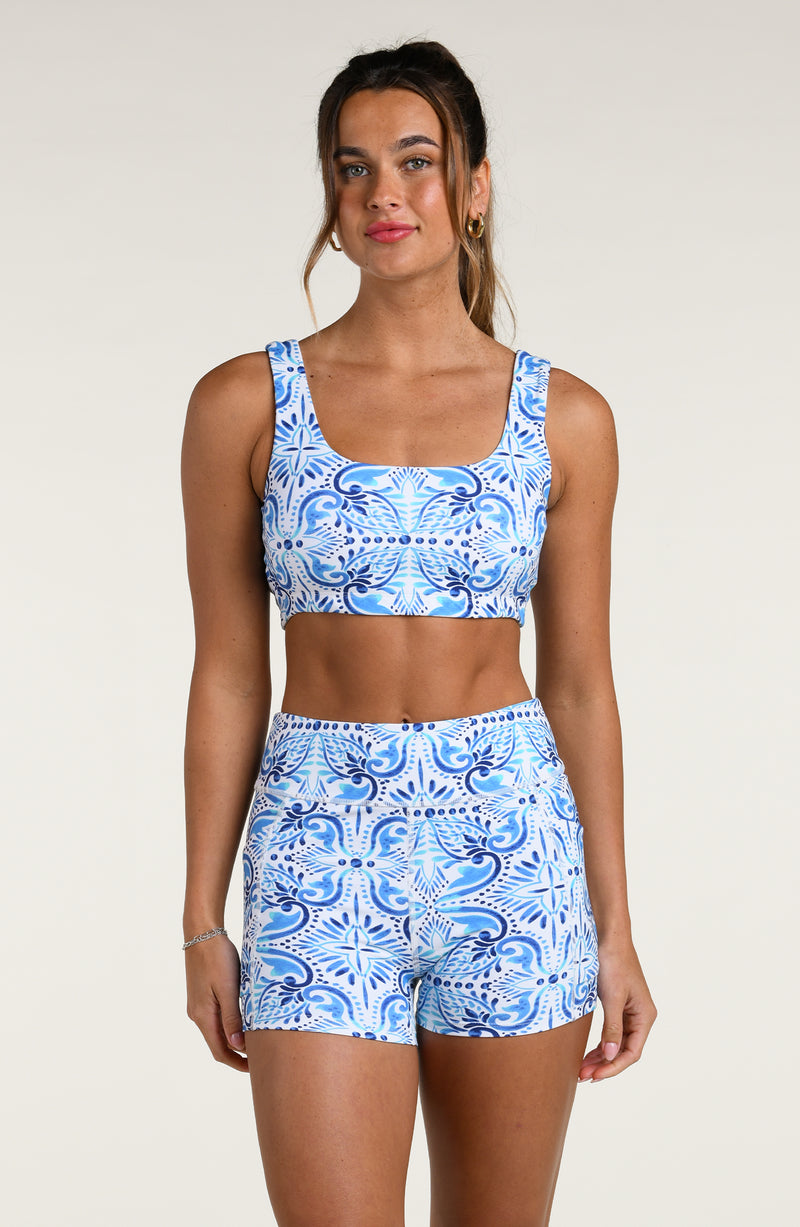 Woman wearing a blue and white patterned sports bra and matching biker shorts against a white background