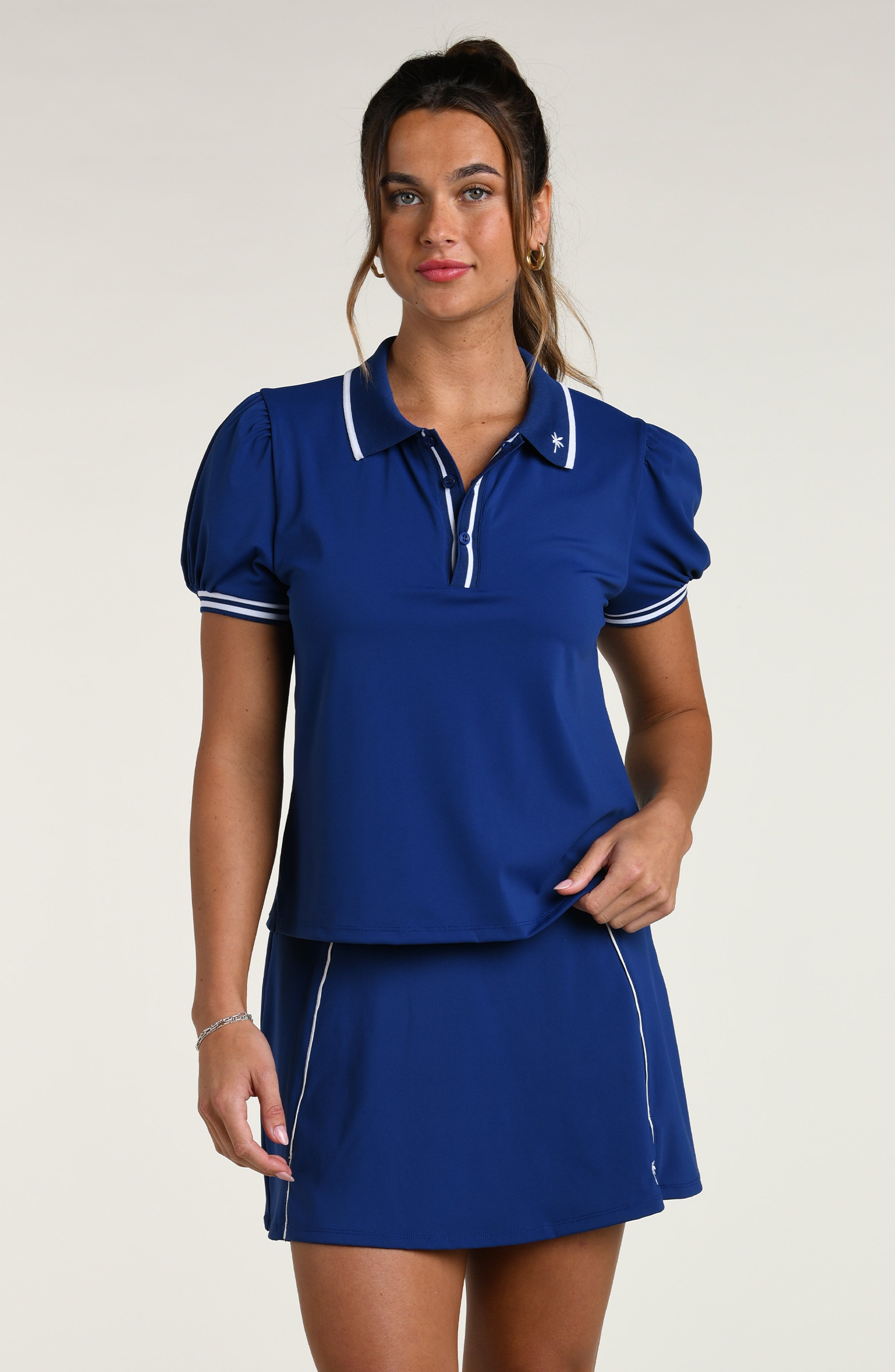 Woman wearing a blue polo shirt and skirt set against a white background