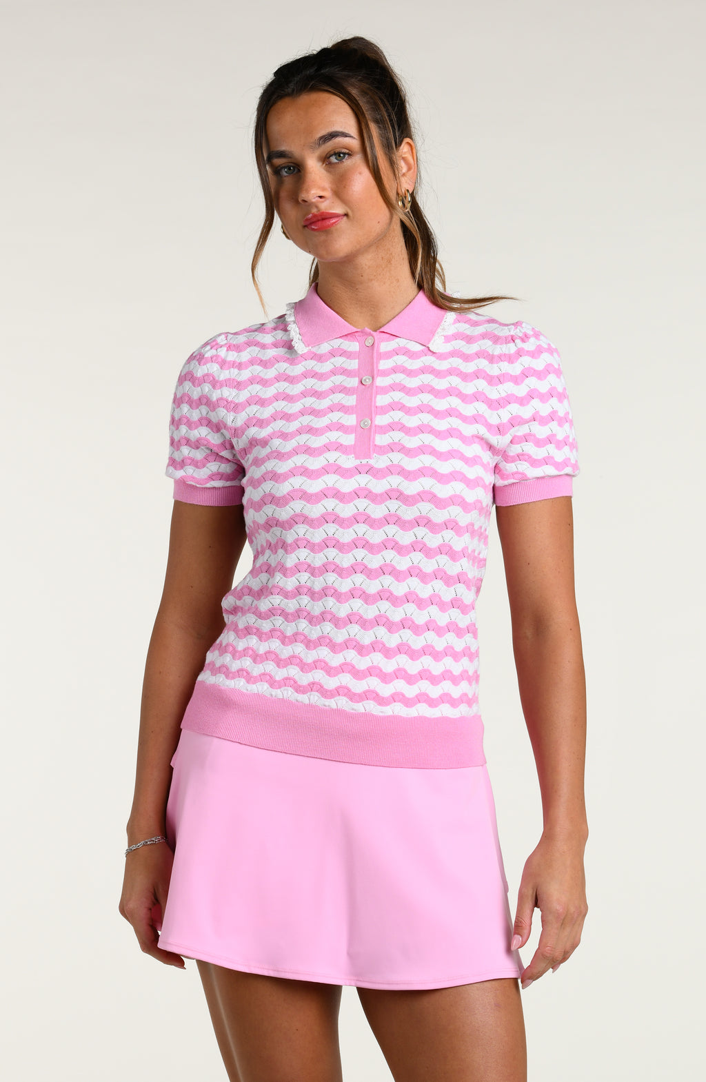 Woman wearing a pink and white multicolored short sleeve top and pink swim skort against a white background.