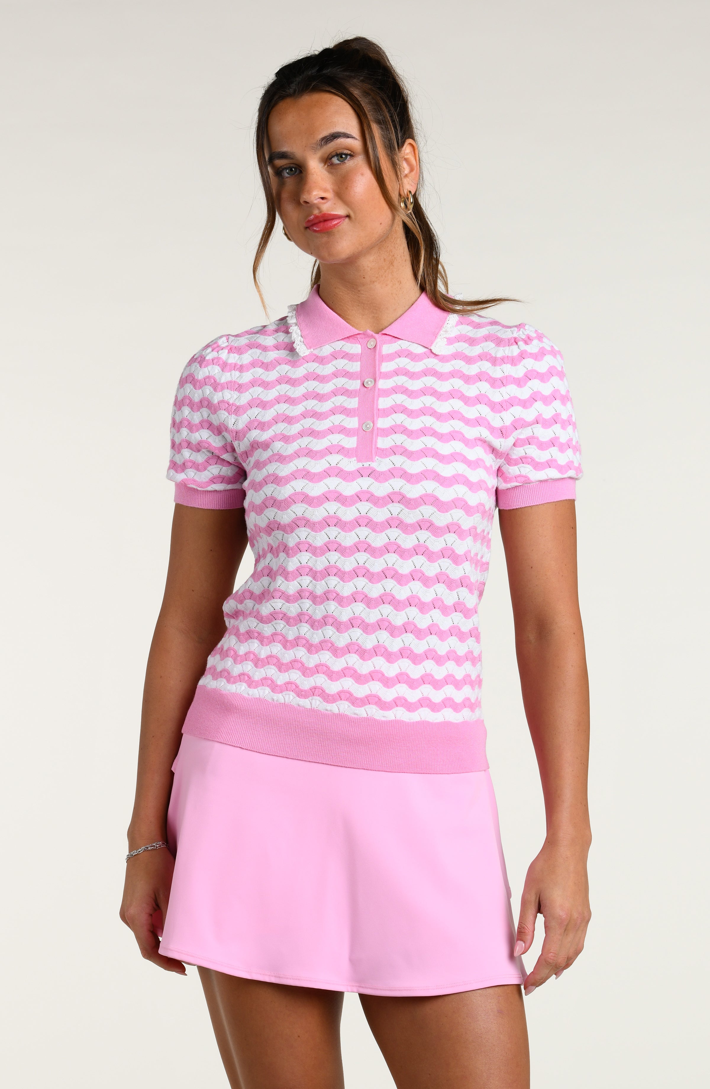 Woman wearing a pink and white multicolored short sleeve top and pink swim skort against a white background.