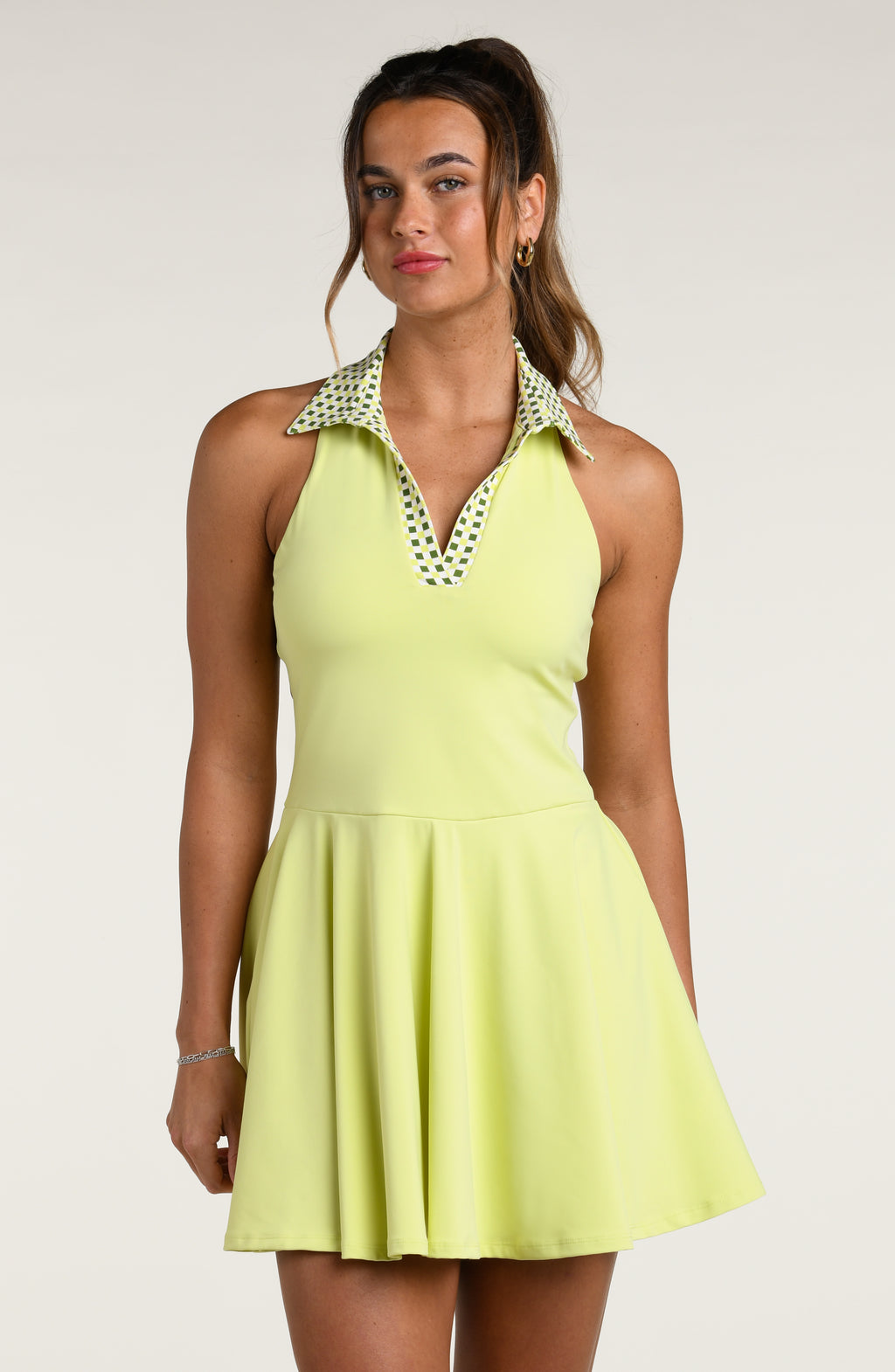 Woman wearing a lime green tennis dress with a patterned collar against a white background