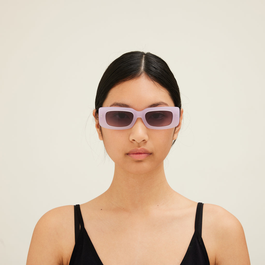 Woman wearing pink sunglasses with dark lenses on a white background