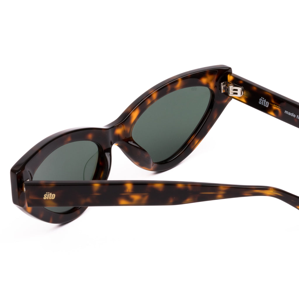 Cat-eye sunglasses with tortoiseshell frame and dark lenses on a white background