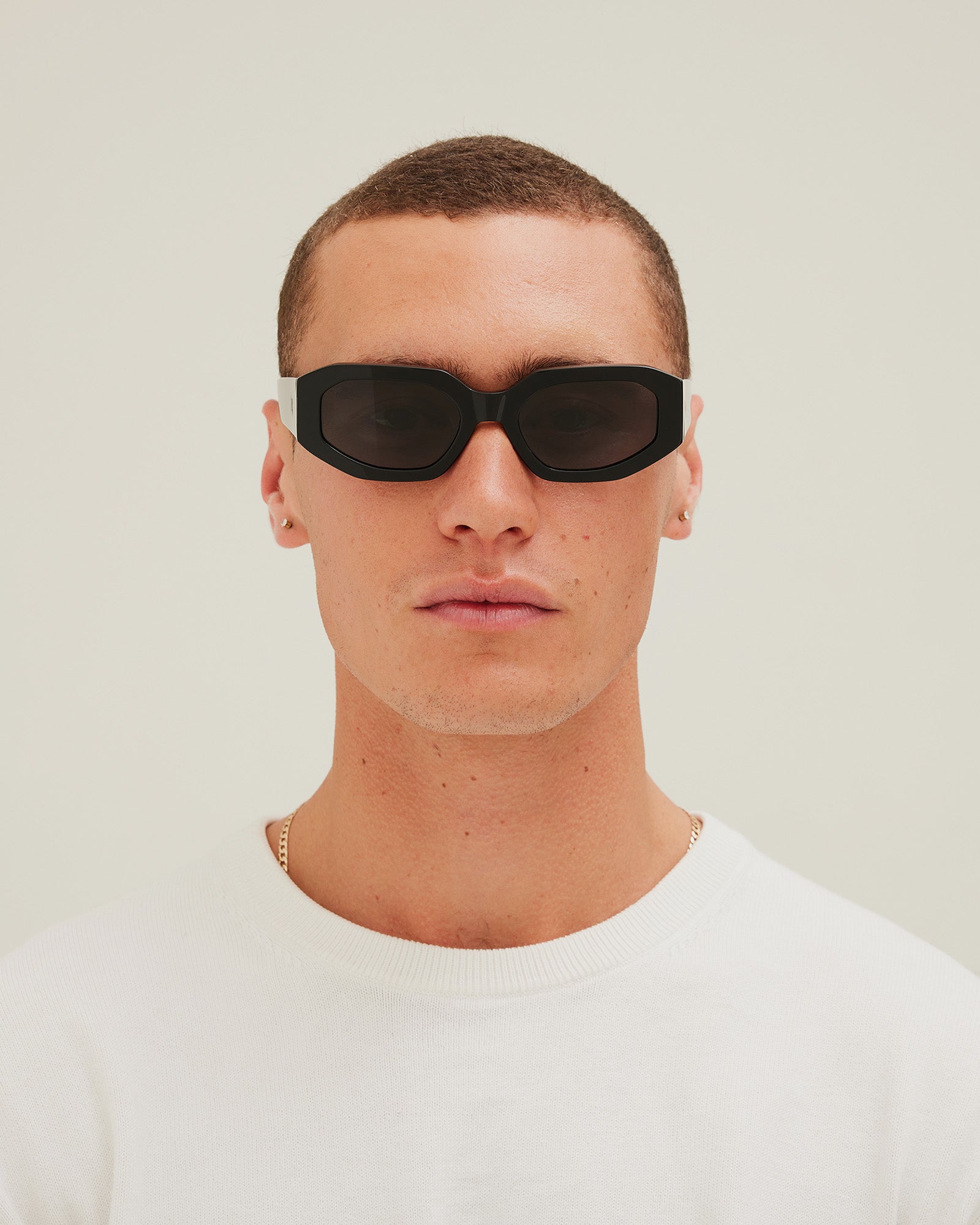 Man wearing black sunglasses with gray lenses on a white background