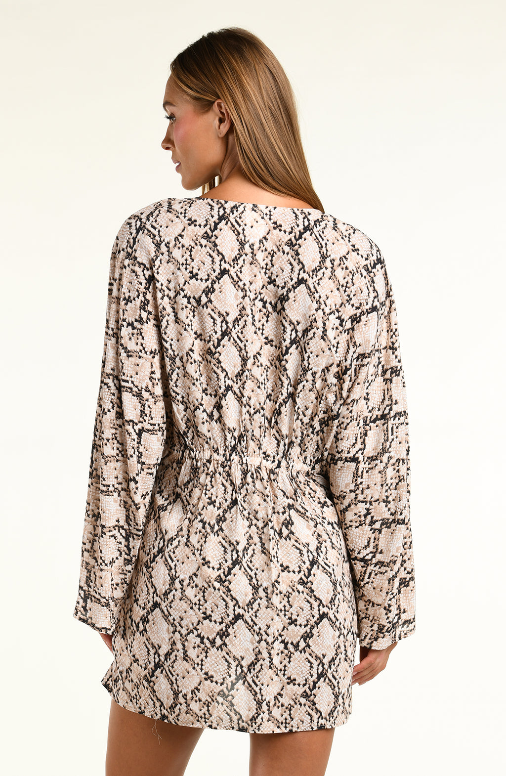A woman modeling a long-sleeve tunic with a beige, black, and brown snakeskin pattern against a plain light background.