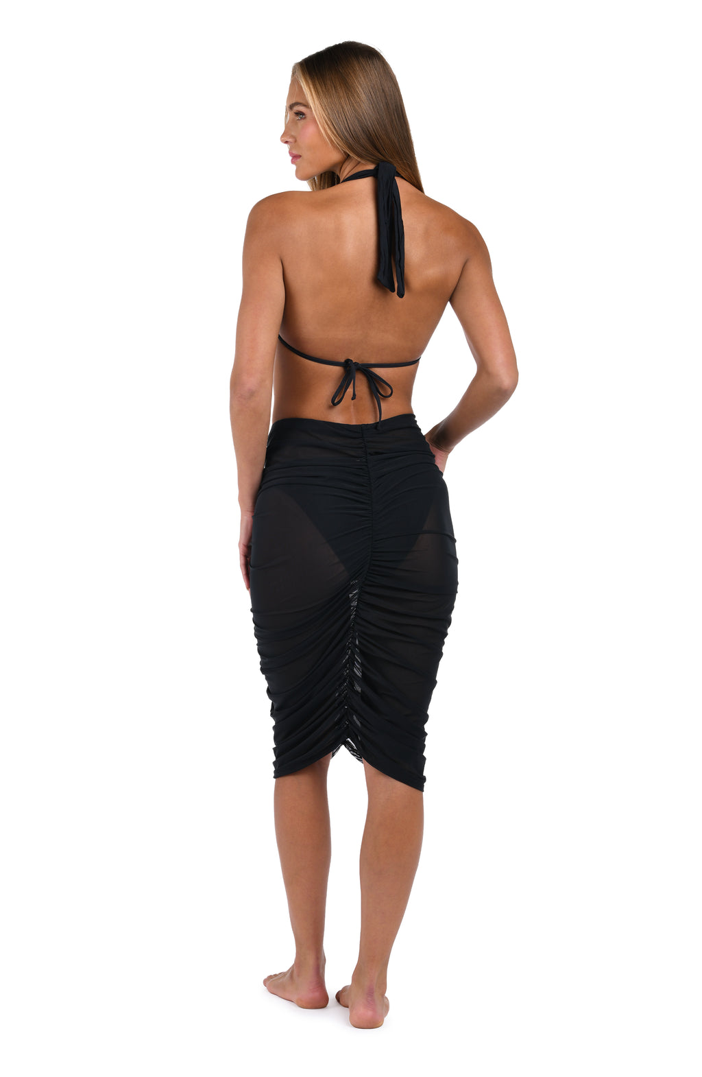 Woman wearing a black bikini top and black sarong on a white background