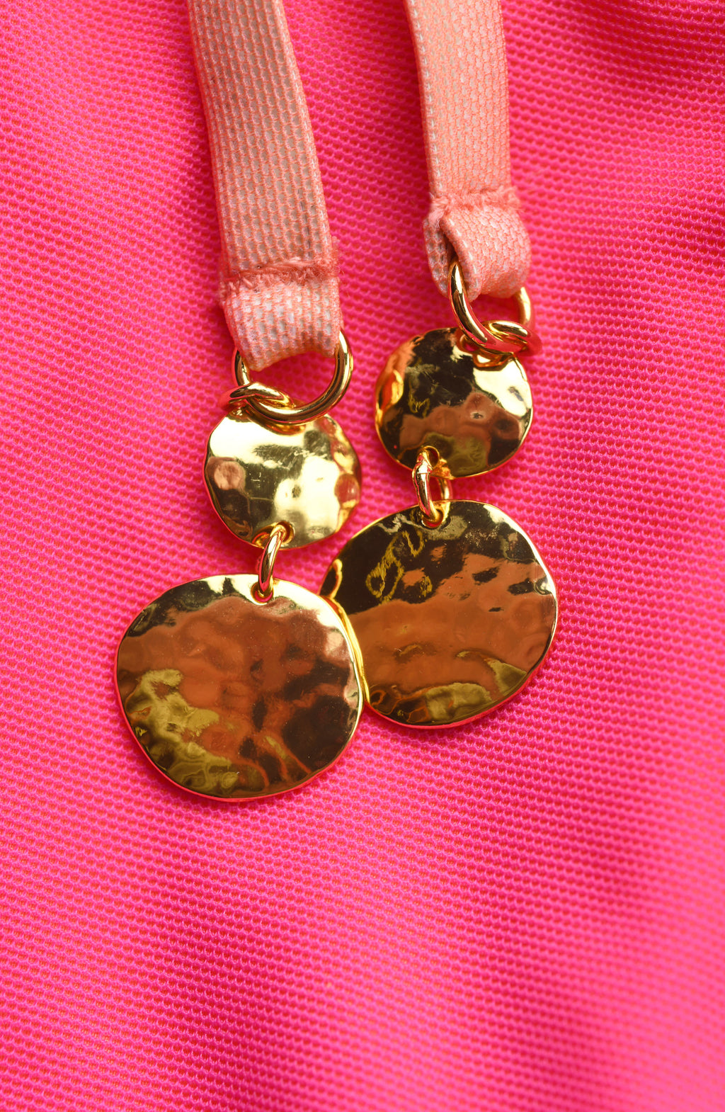 Close-up of gold tassel ends against a pink background. 