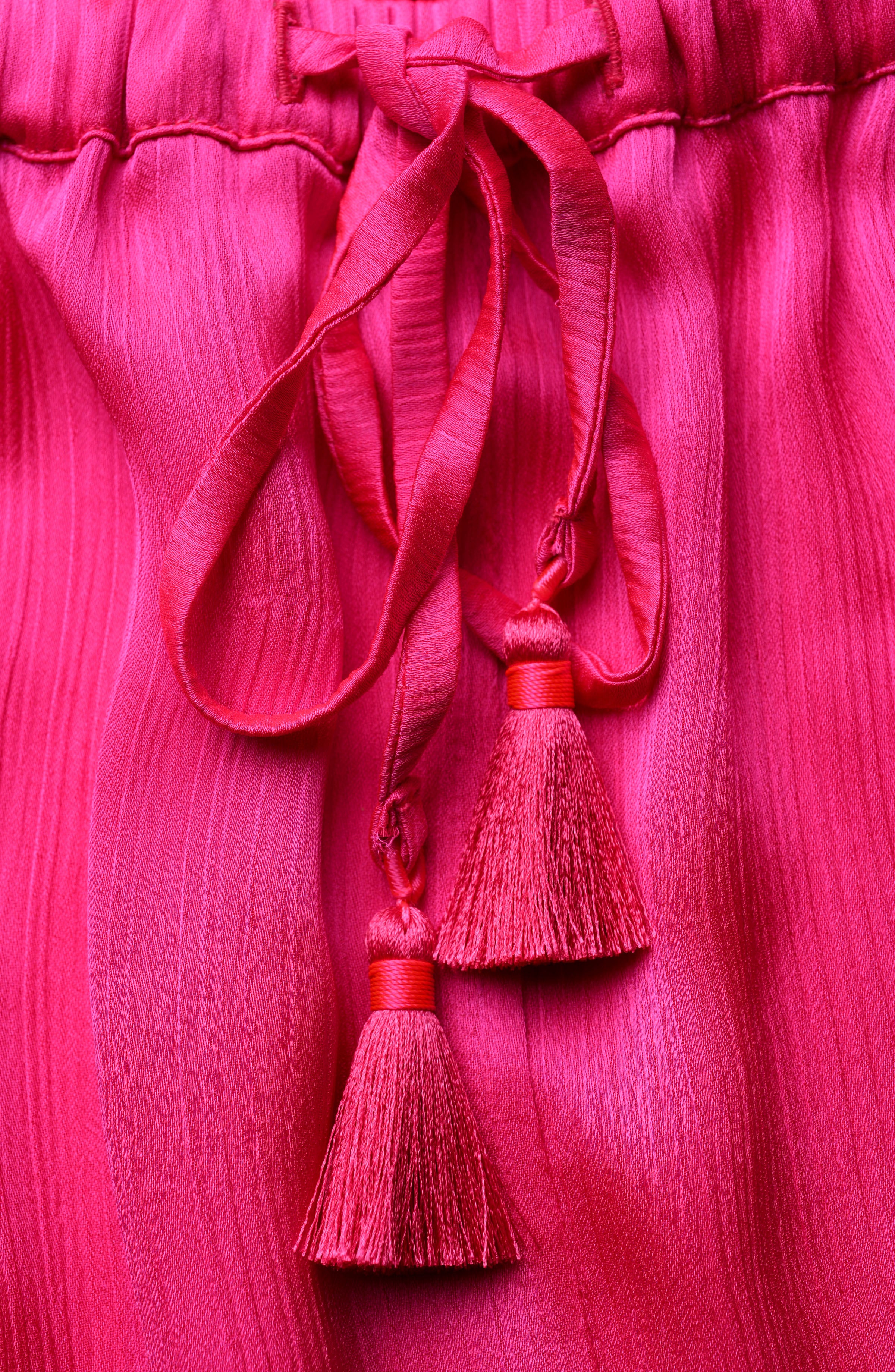 Close-up of a bright pink fabric with tassels on a matching pink background