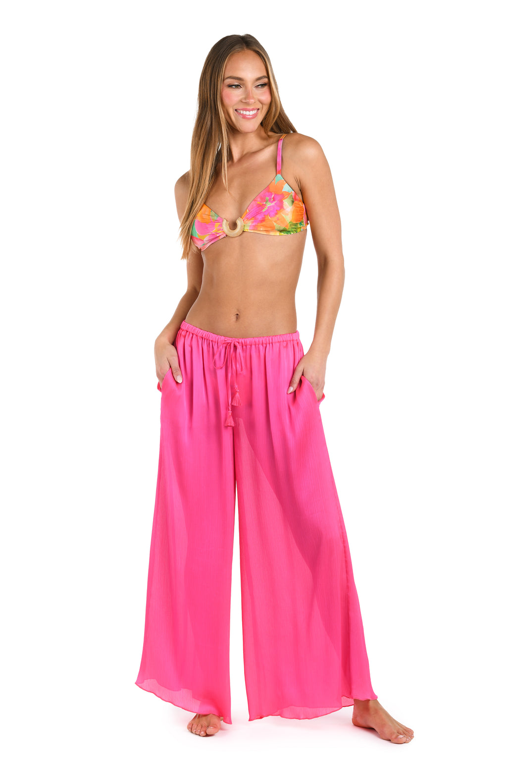 Woman wearing a bright pink bikini top and bright pink pants on a white background