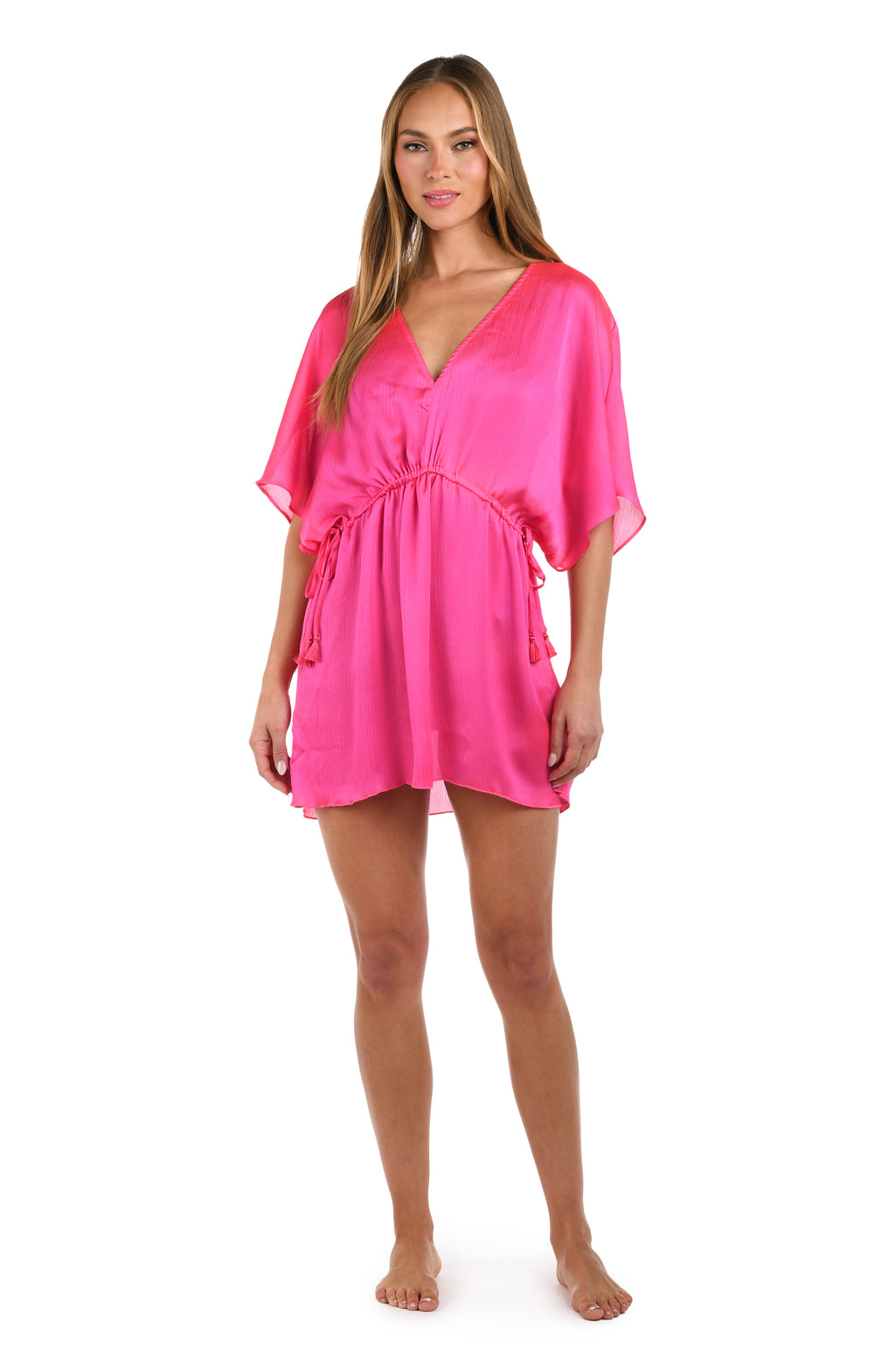 Full body front image of model wearing a solid bright pink V-neck tunic cover up.        