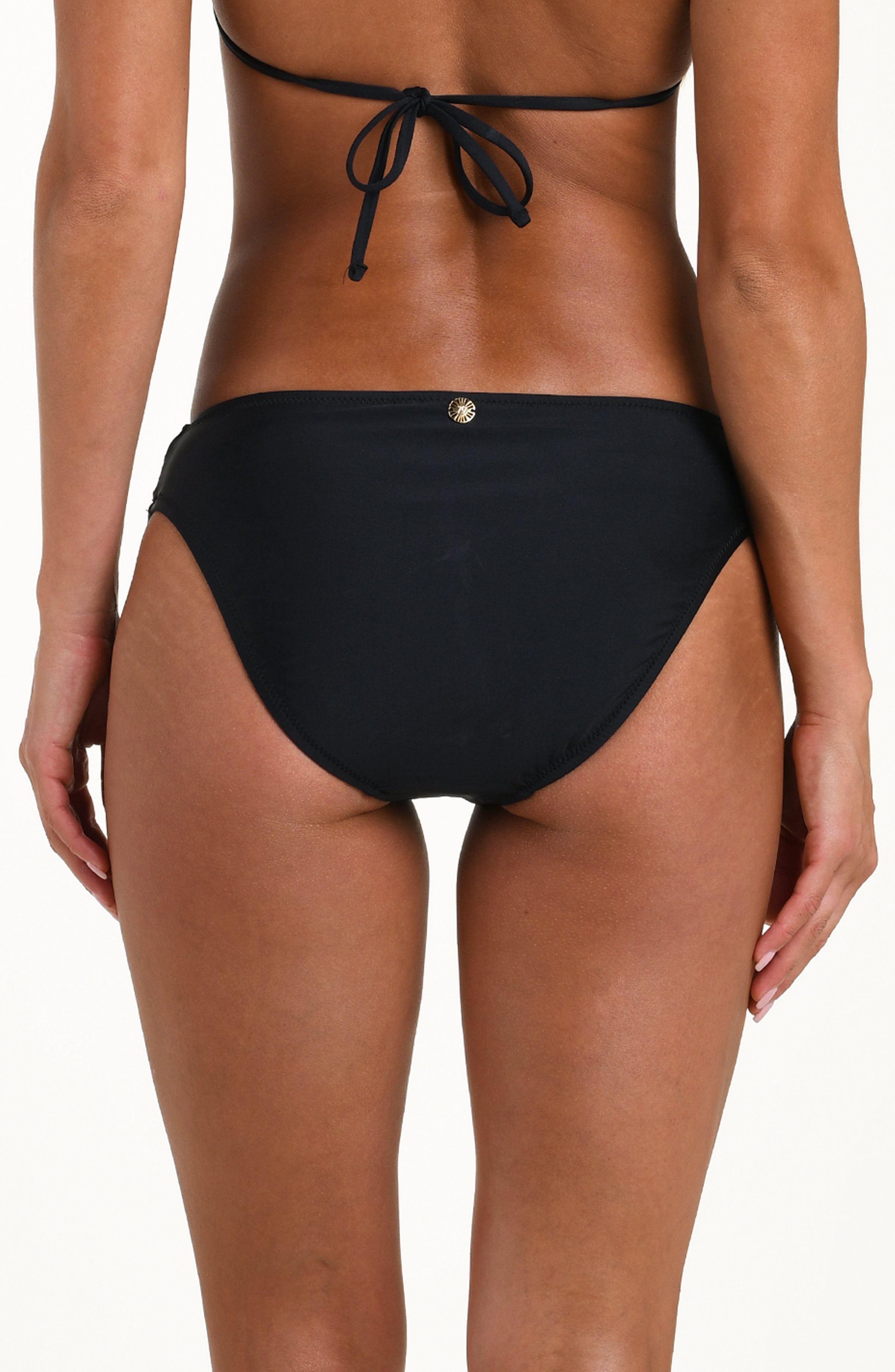 Back image of model wearing a solid black bikini bottom with a gold charm at center and moderate rear coverage.