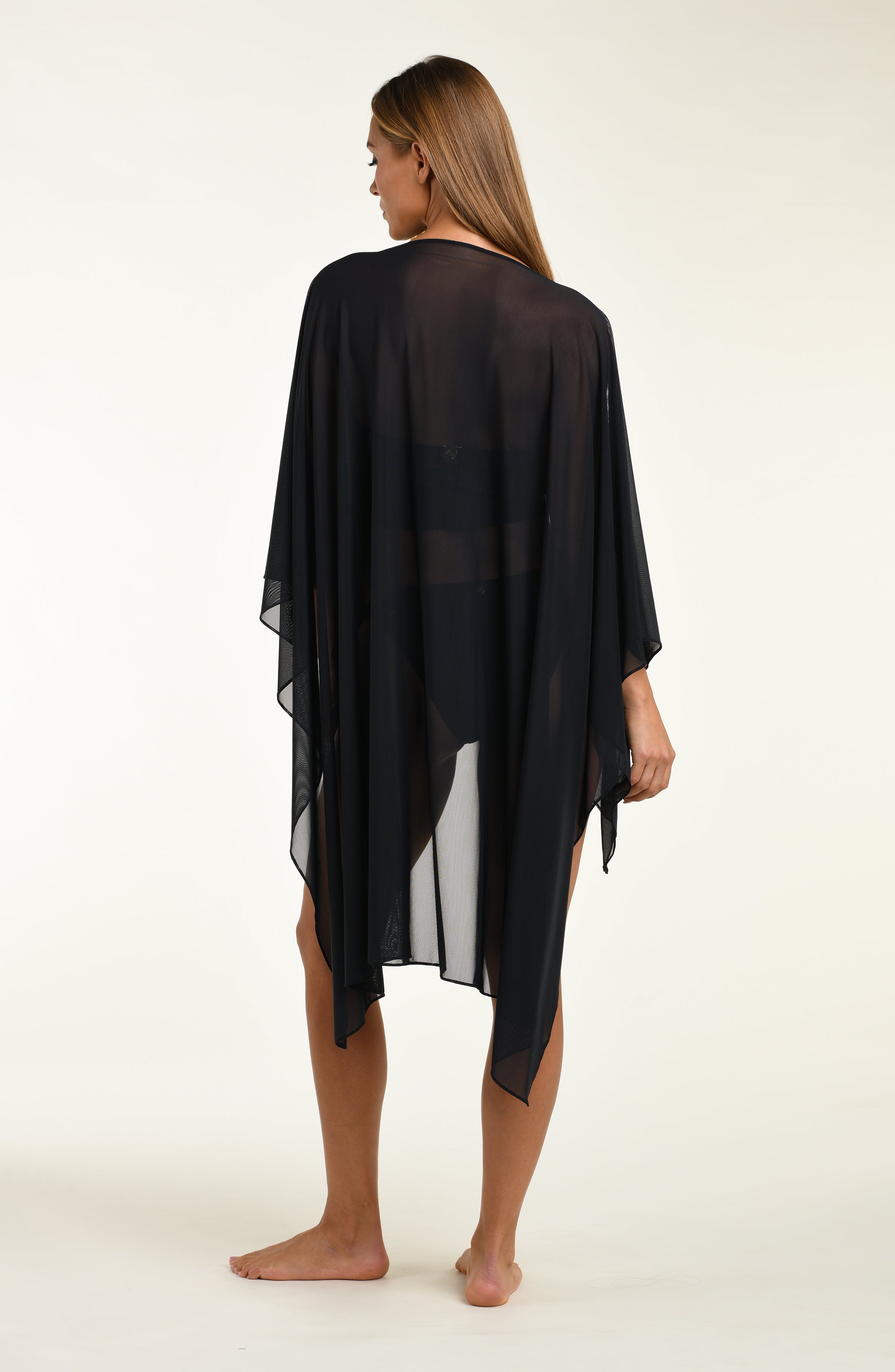 Woman wearing a black poncho against a white background