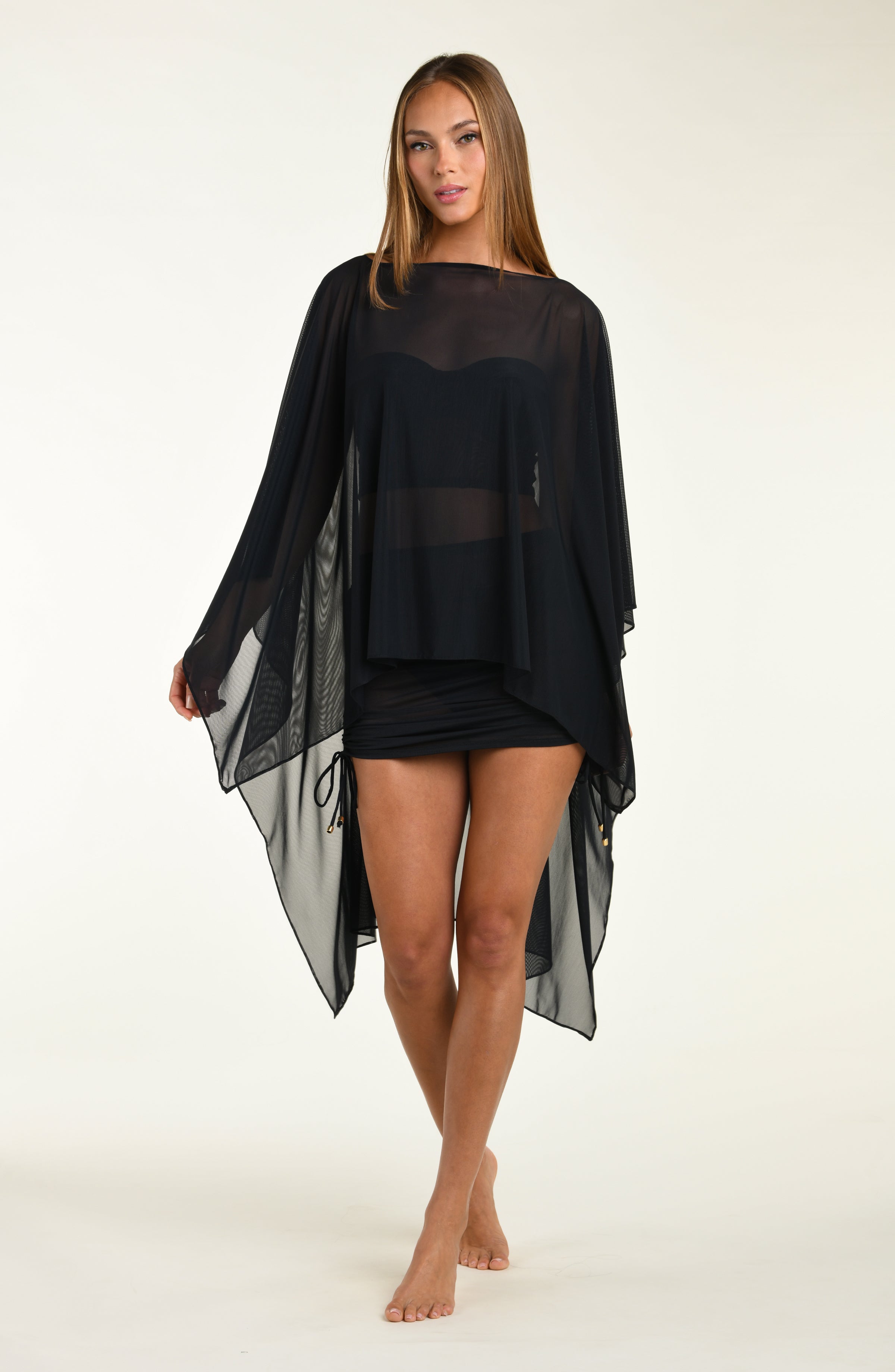 Woman wearing a black poncho against a white background