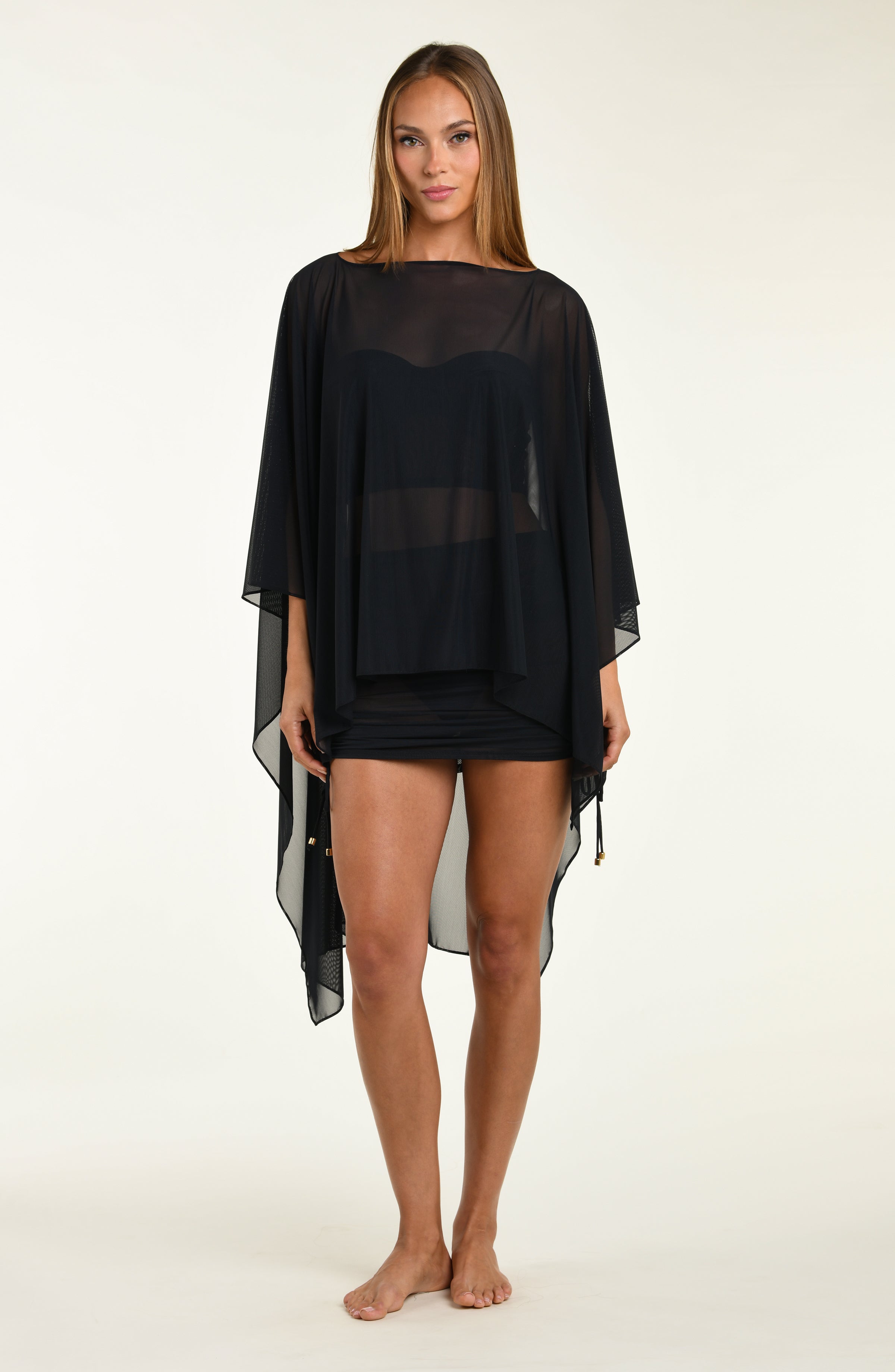 Woman wearing a black poncho against a white background