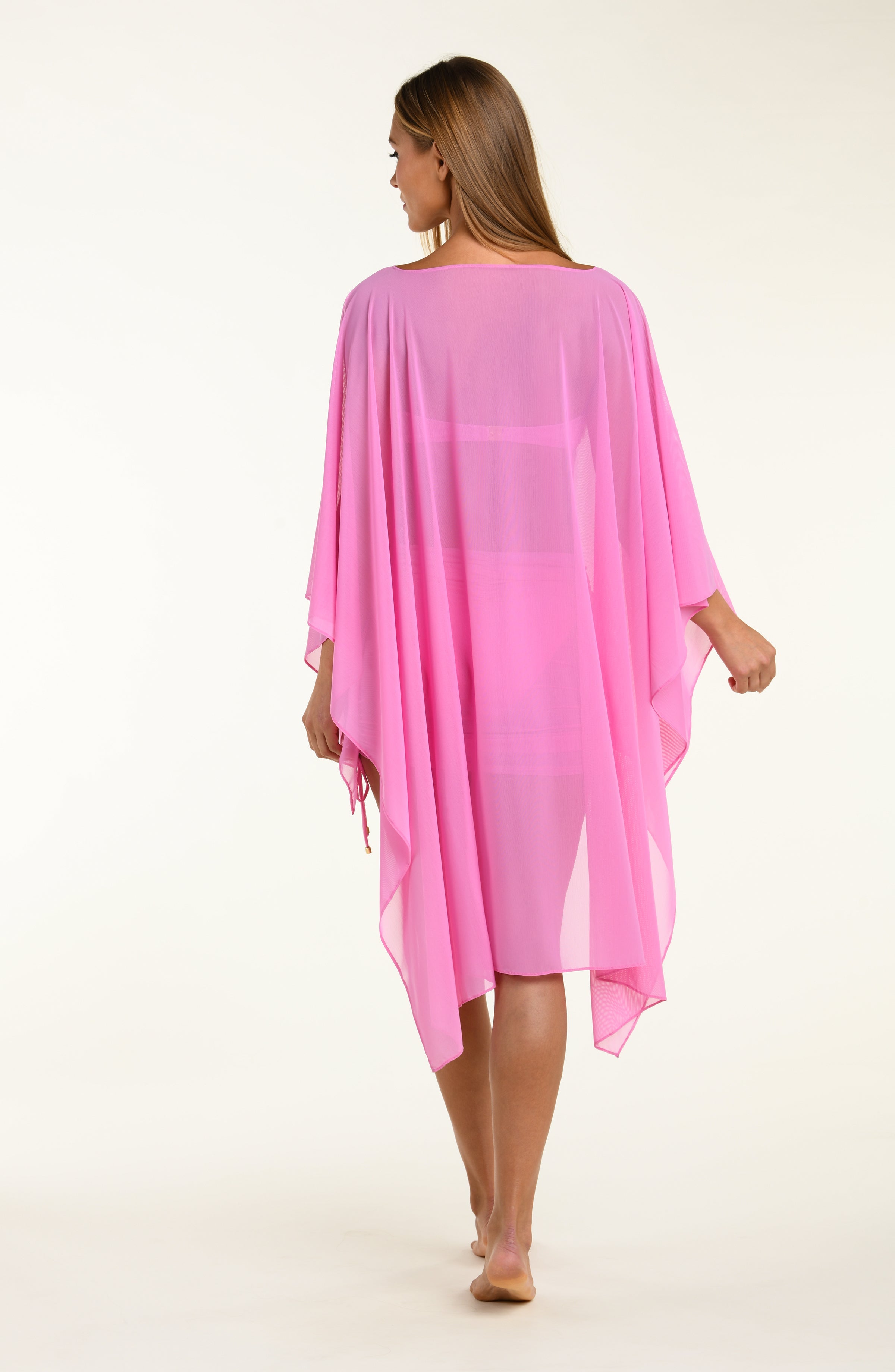 Woman wearing a pink poncho against a white background