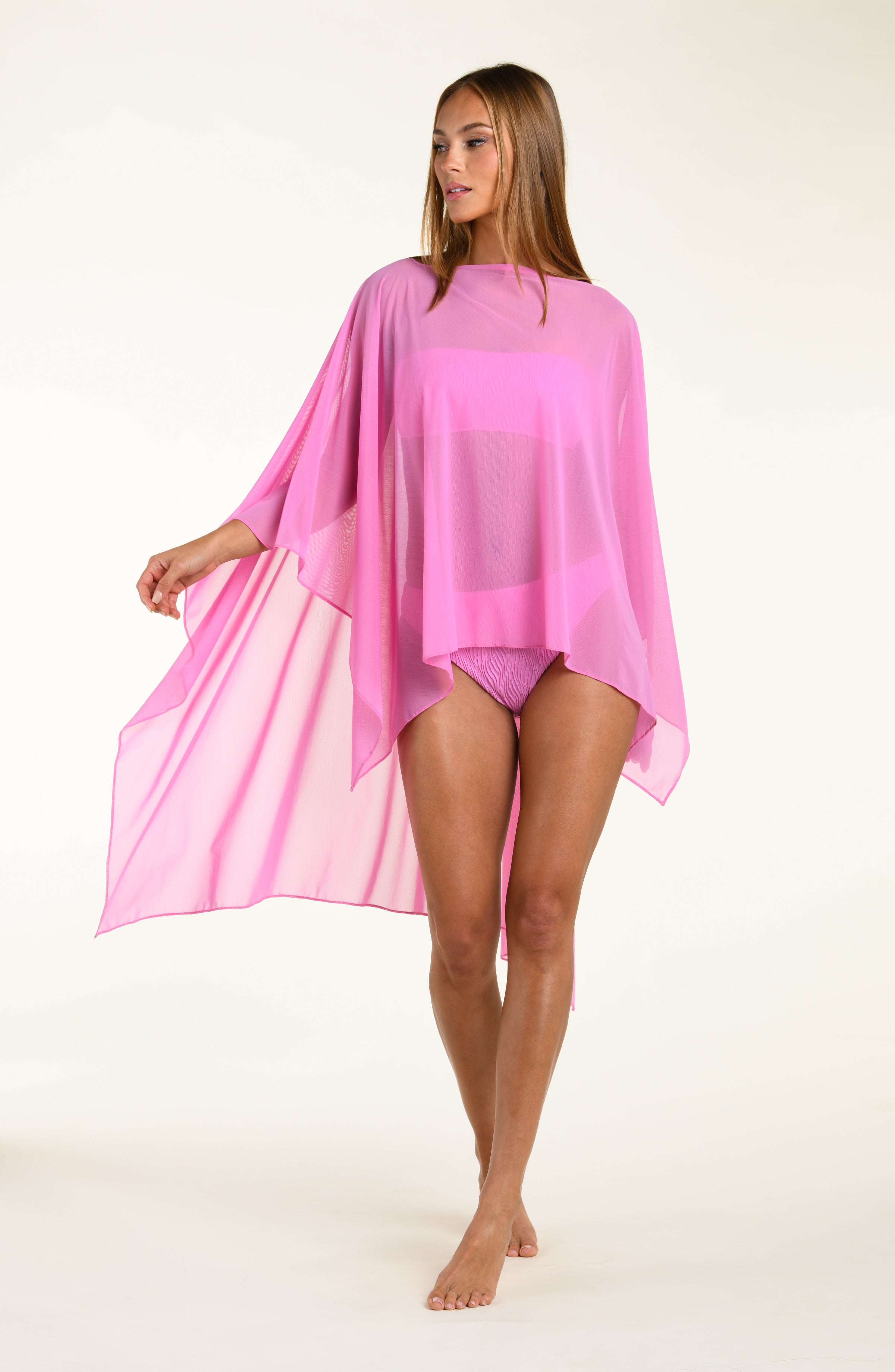 Woman wearing a pink poncho against a white background