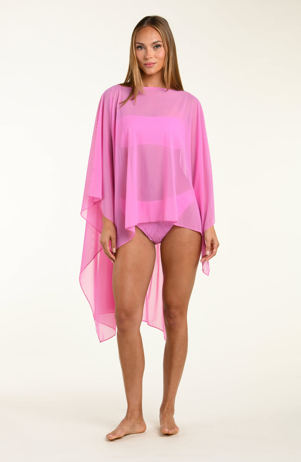Woman wearing a pink poncho against a white background