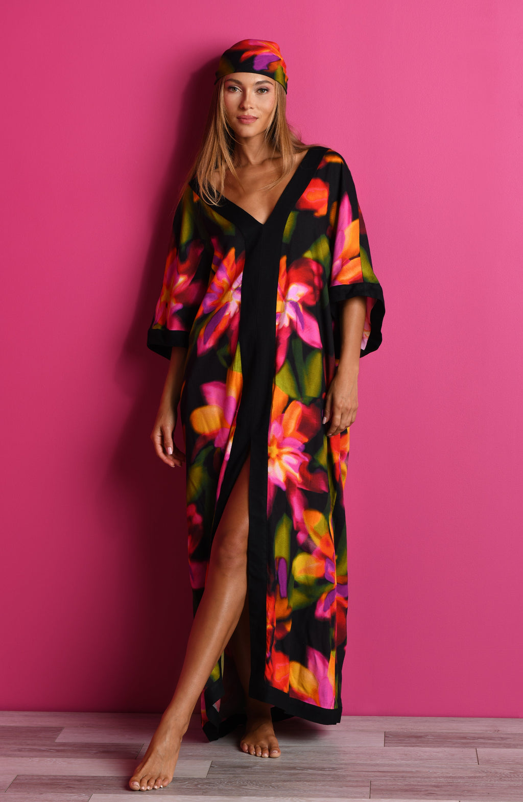 Lifestyle image of model wearing a long maxi dress-style cover-up featuring a deep V-neckline and vibrant oversized floral print. 