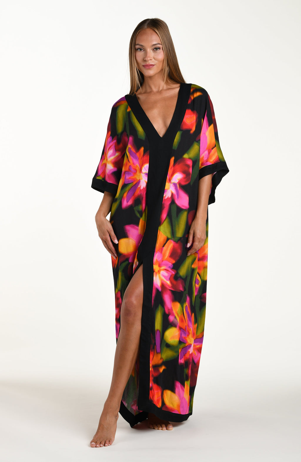 Full body front image of model wearing a long maxi dress-style cover-up featuring a deep V-neckline and vibrant oversized floral print. 