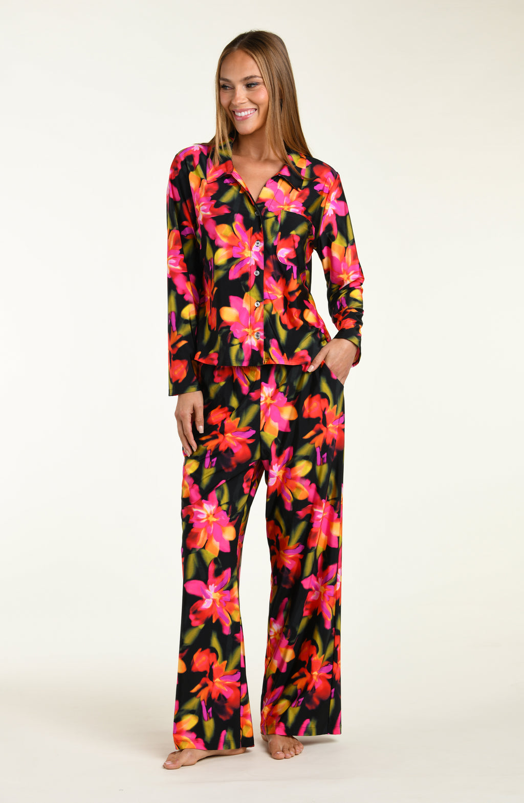 Woman wearing a colorful floral shirt and pant pajama set on a white background