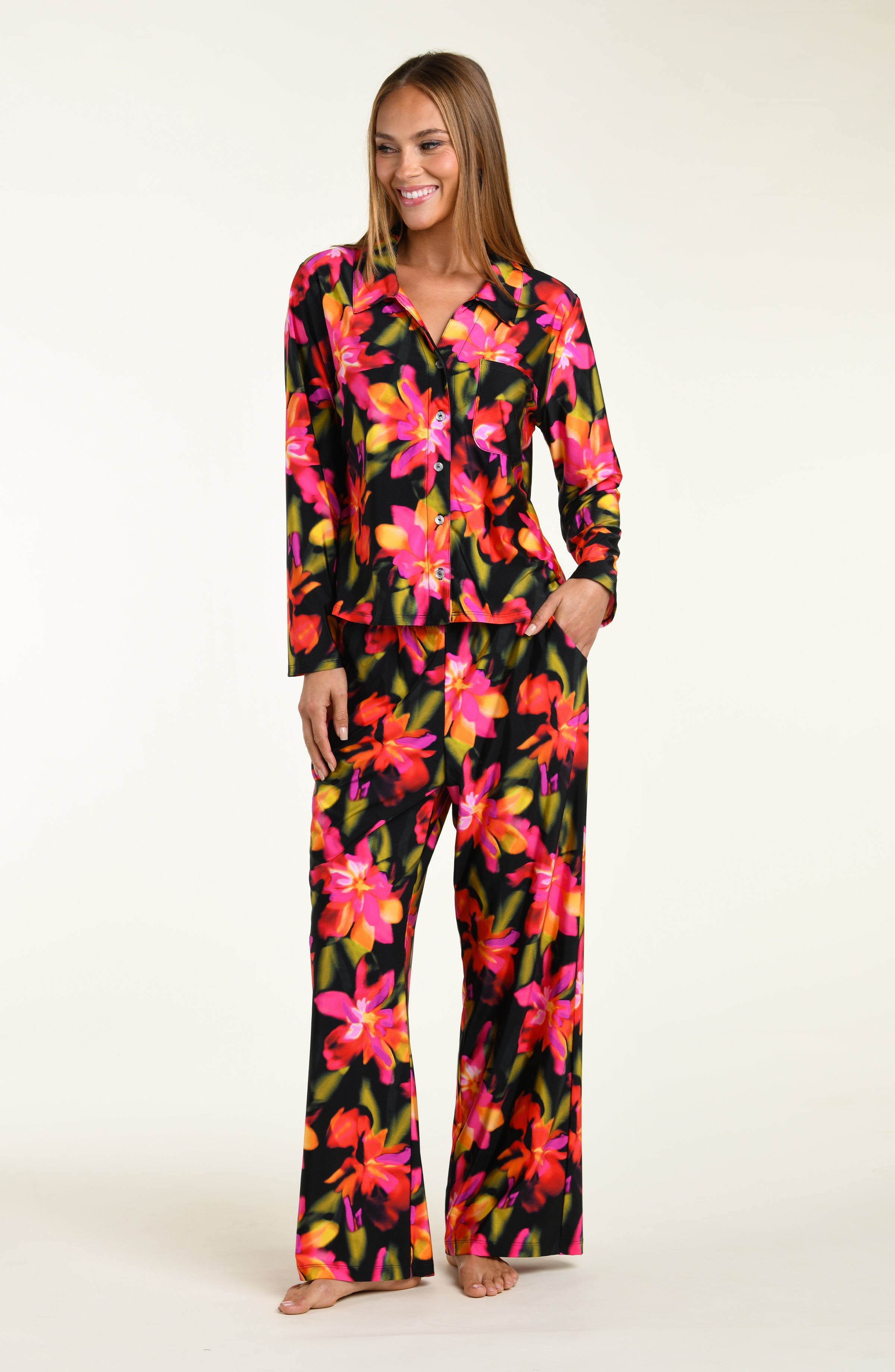 Woman wearing a colorful floral shirt and pant pajama set on a white background
